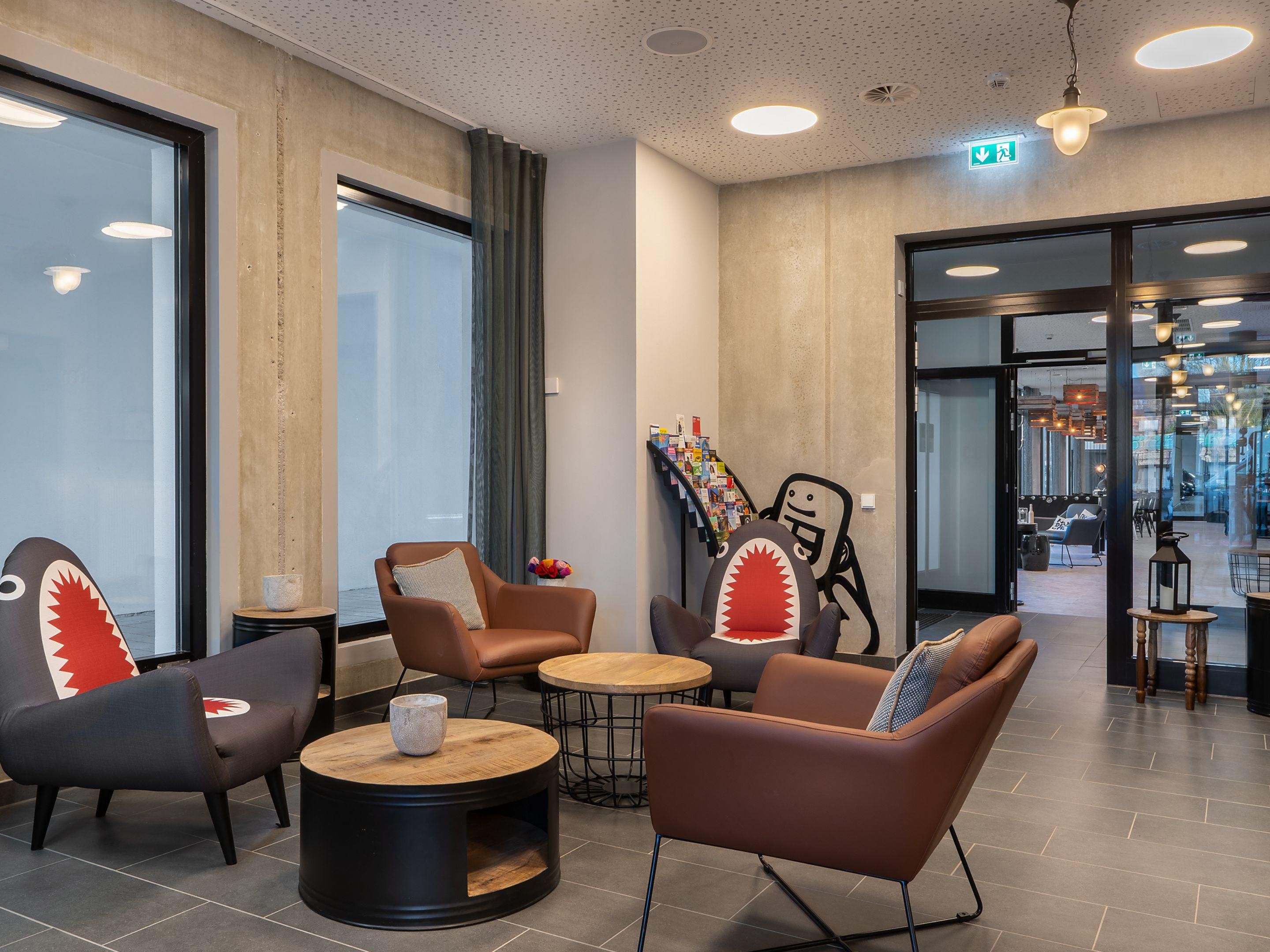 The hotel's interior combines North German harbor flair with a modern style. Industrial and maritime elements, such as rope lamps and cabin tables, create an inviting atmosphere. The blend of Nordic elegance and rugged industrial design is enriched by the vibrant graffiti of Rebelzer.
