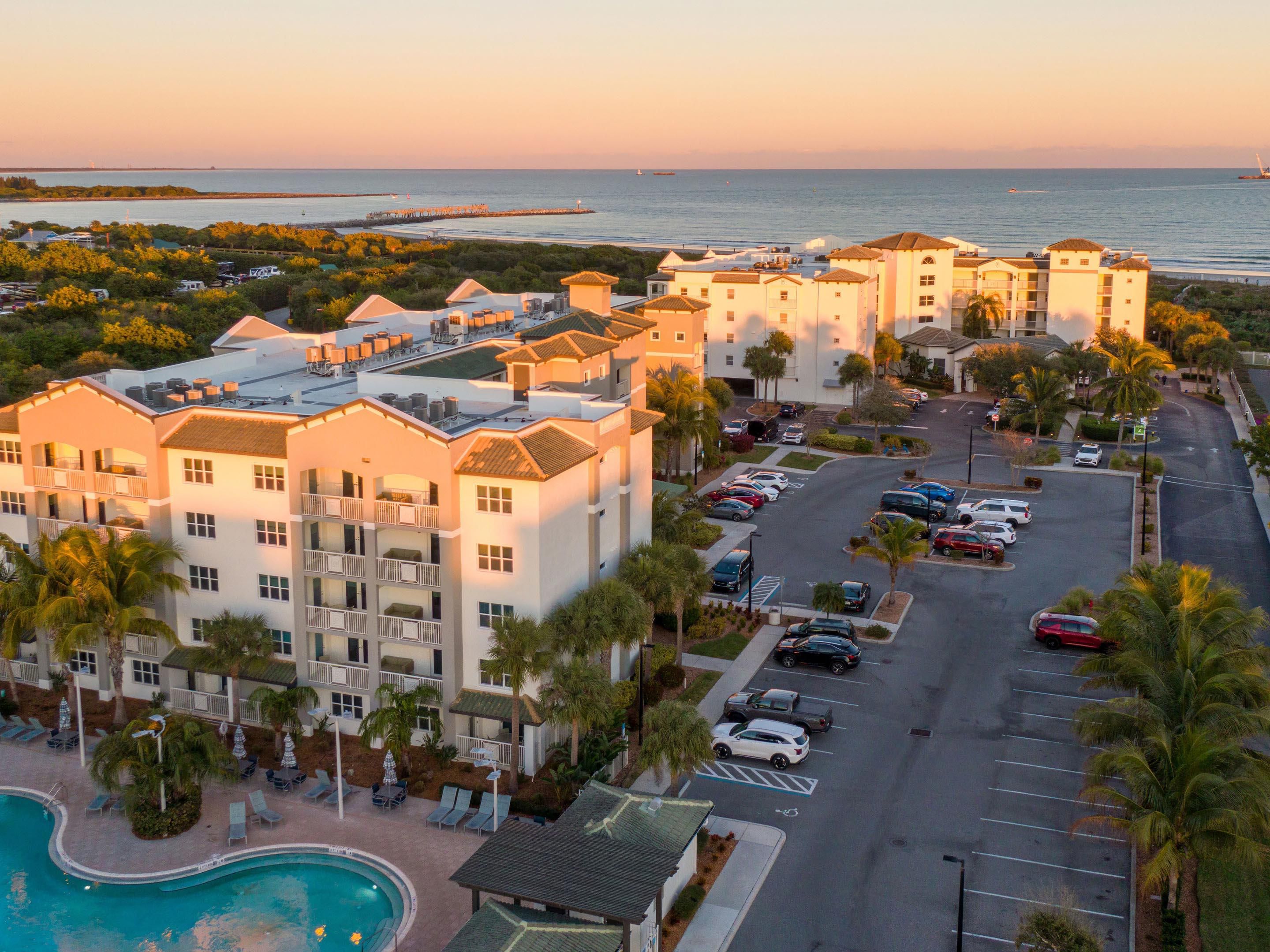 Aerial view of the resort and pool by the ocean at sunset.