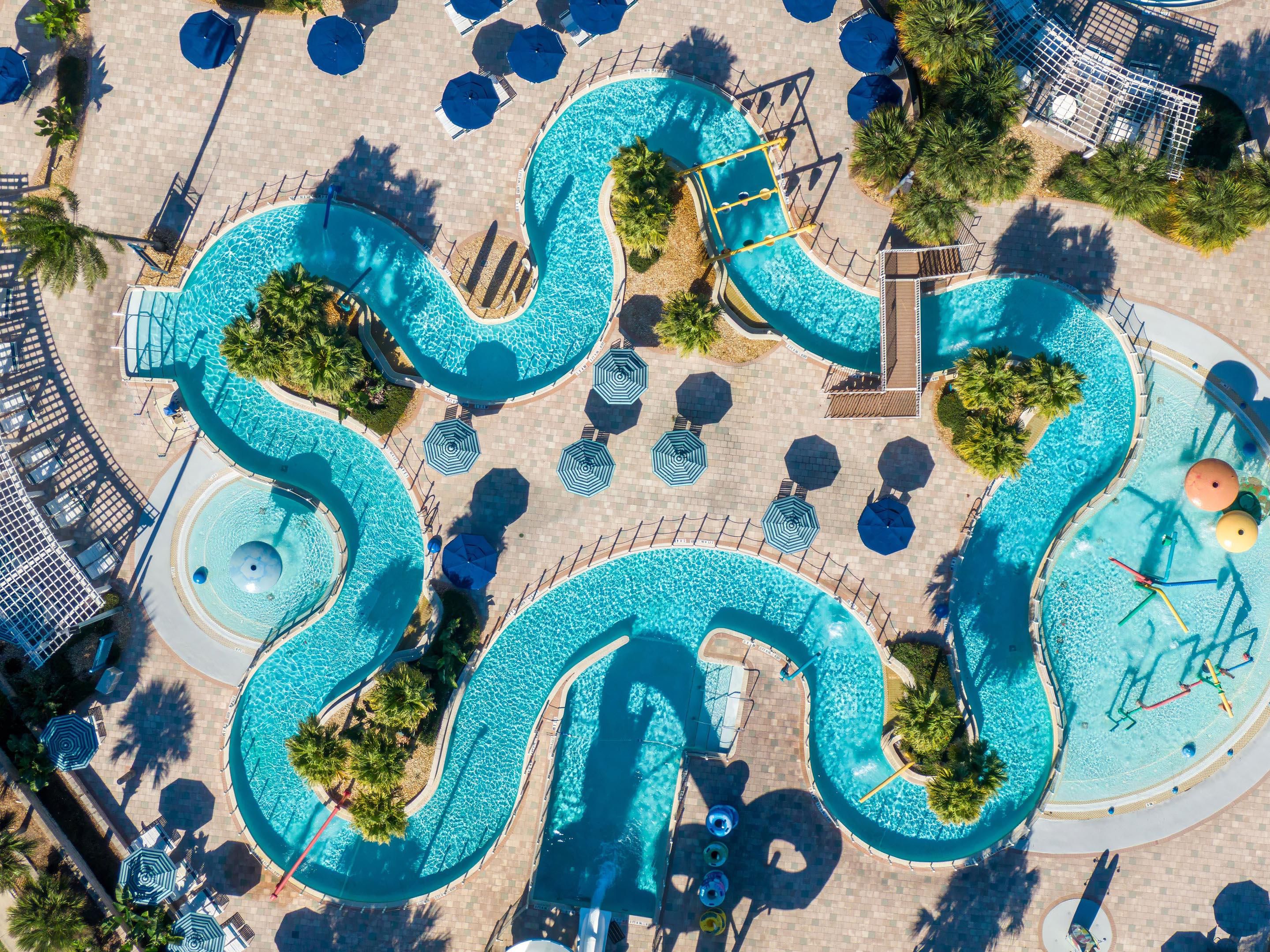 Aerial view of the winding lazy river with palms and umbrellas.