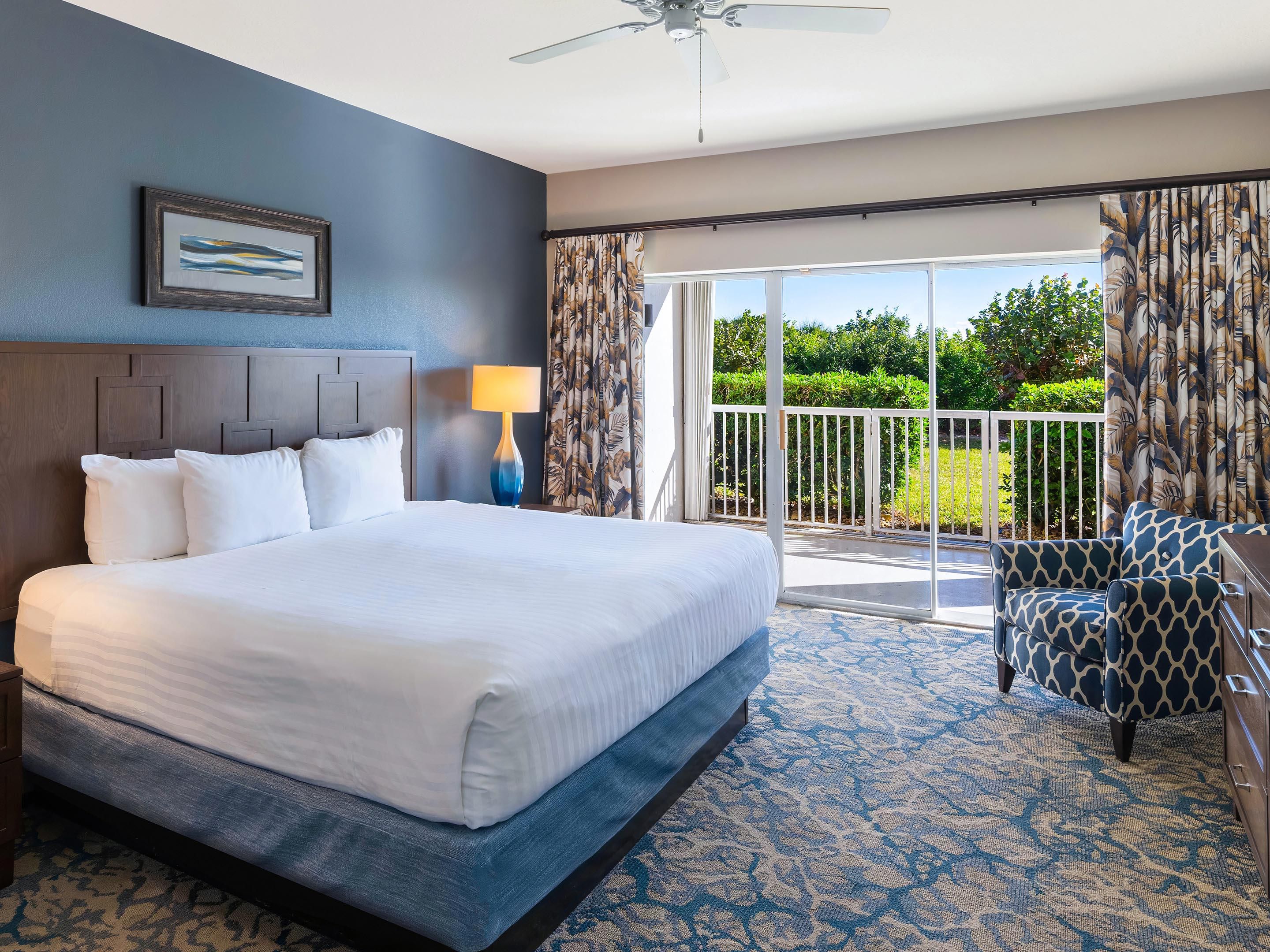 Resort suite with a king bed and balcony access to lush gardens.