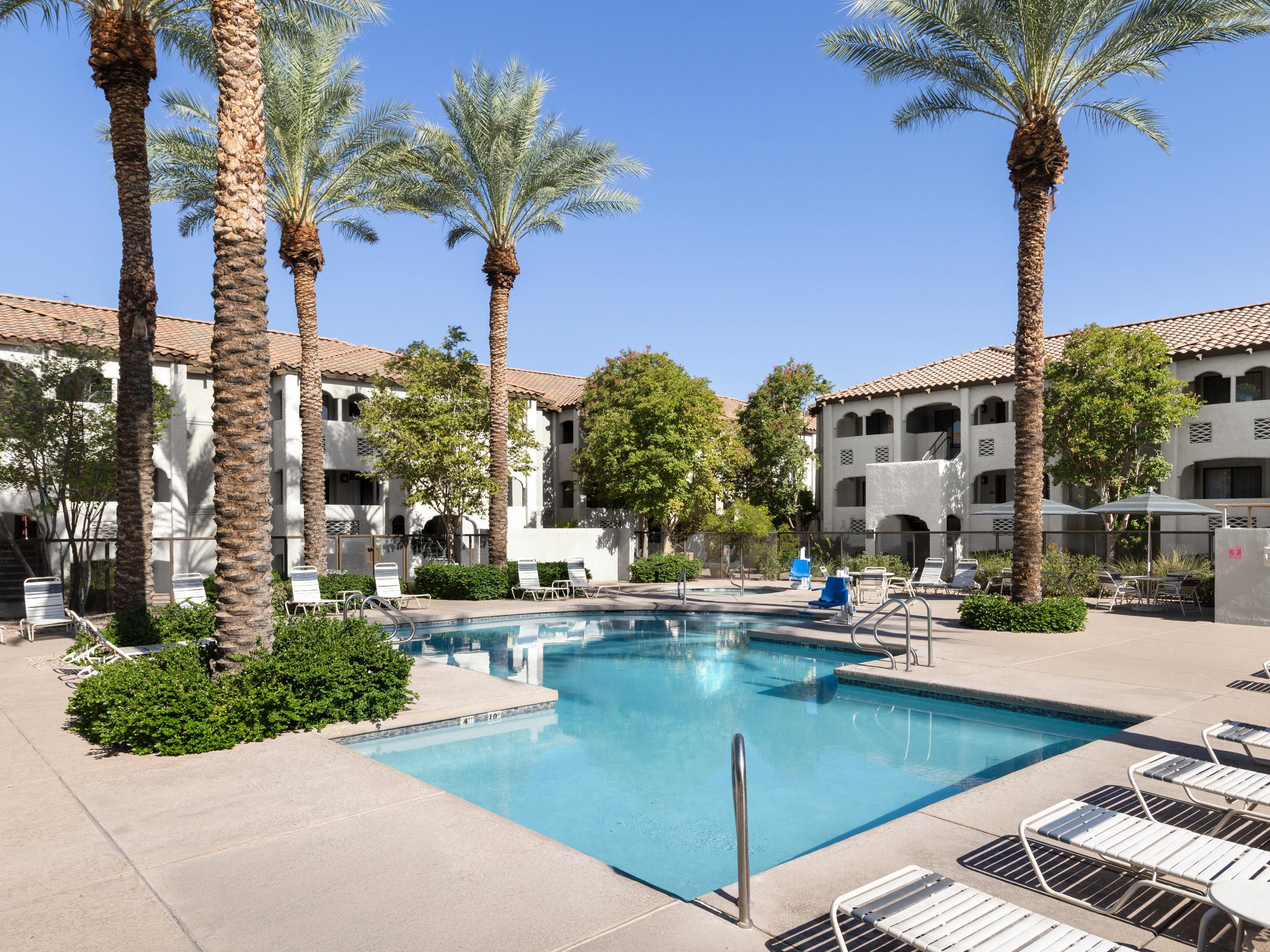 Outdoor pool area with lounge chairs and palm trees