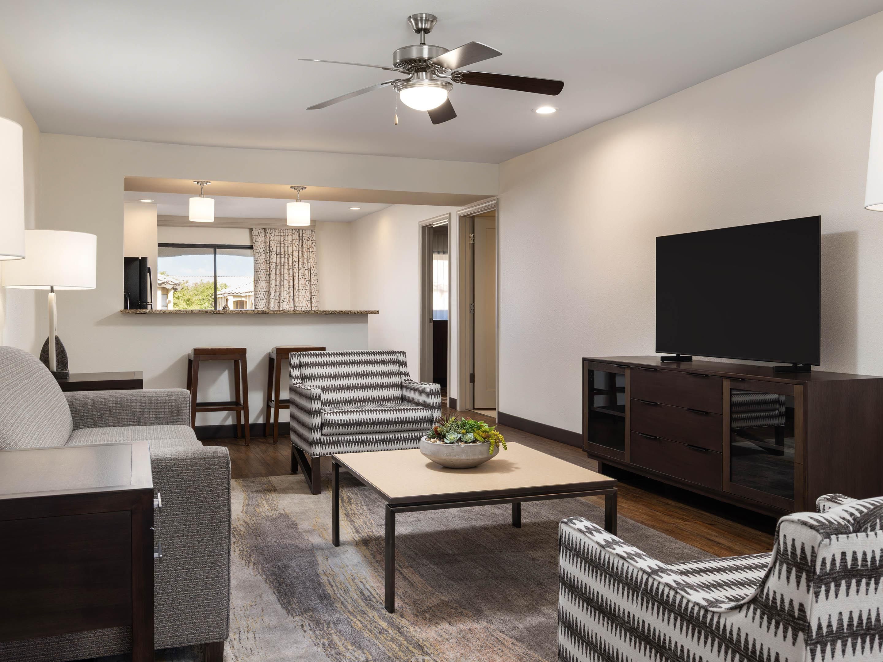 Living room with sofa, chairs, TV, and ceiling fan.