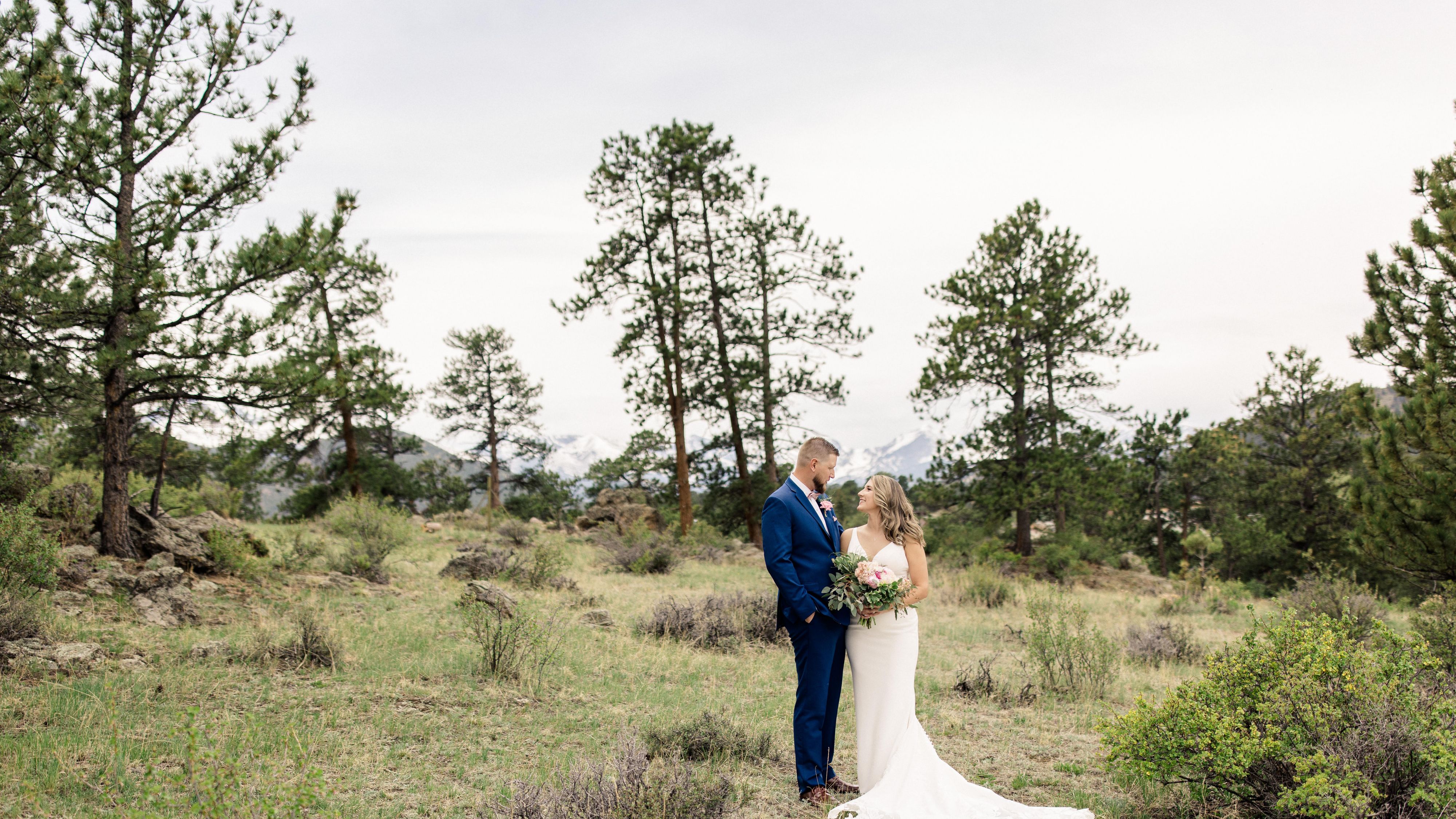 Bride and groom posing for photo in a field of green