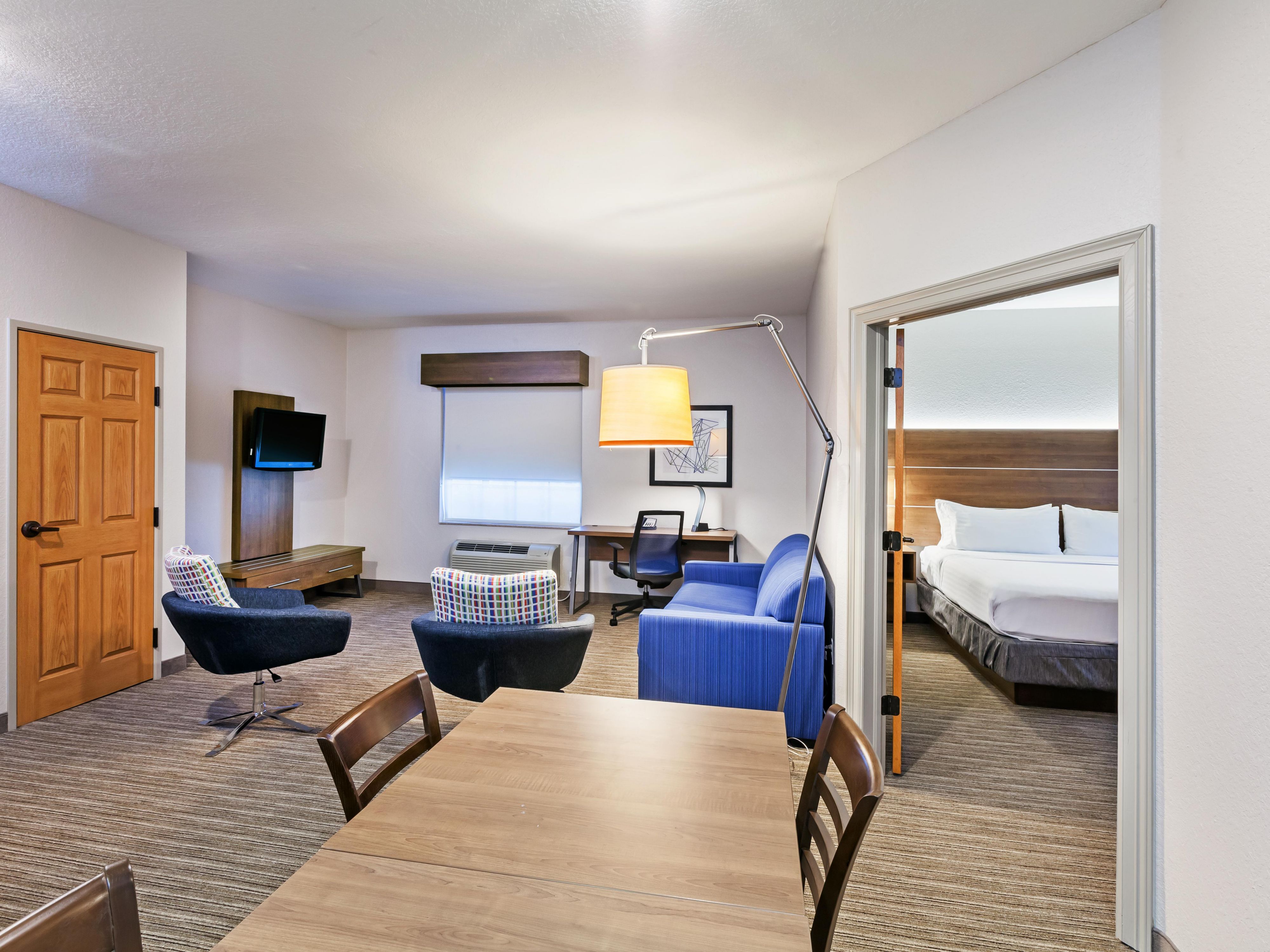 The Family Suite features an open floor plan offering a dining and living room with TV and kitchenette combo with mini fridge, microwave, and Keurig coffee maker. The king bed is located in its own room with closing doors and TV.  A separate room features twin-size bunk beds that flow with the open floor plan, with a TV and Sony PlayStation. 