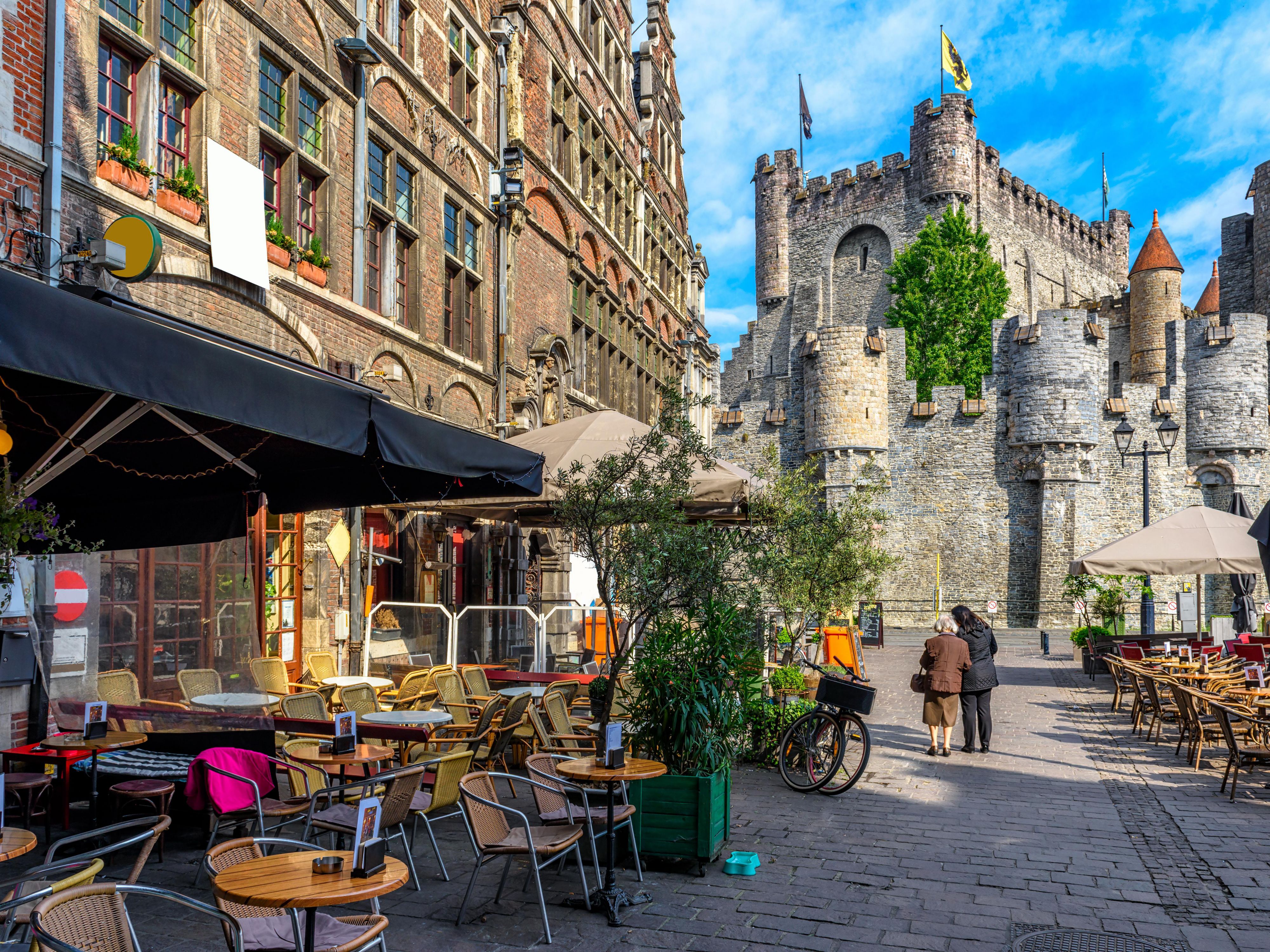 Outdoor café on a cobblestone street near a stone castle.
