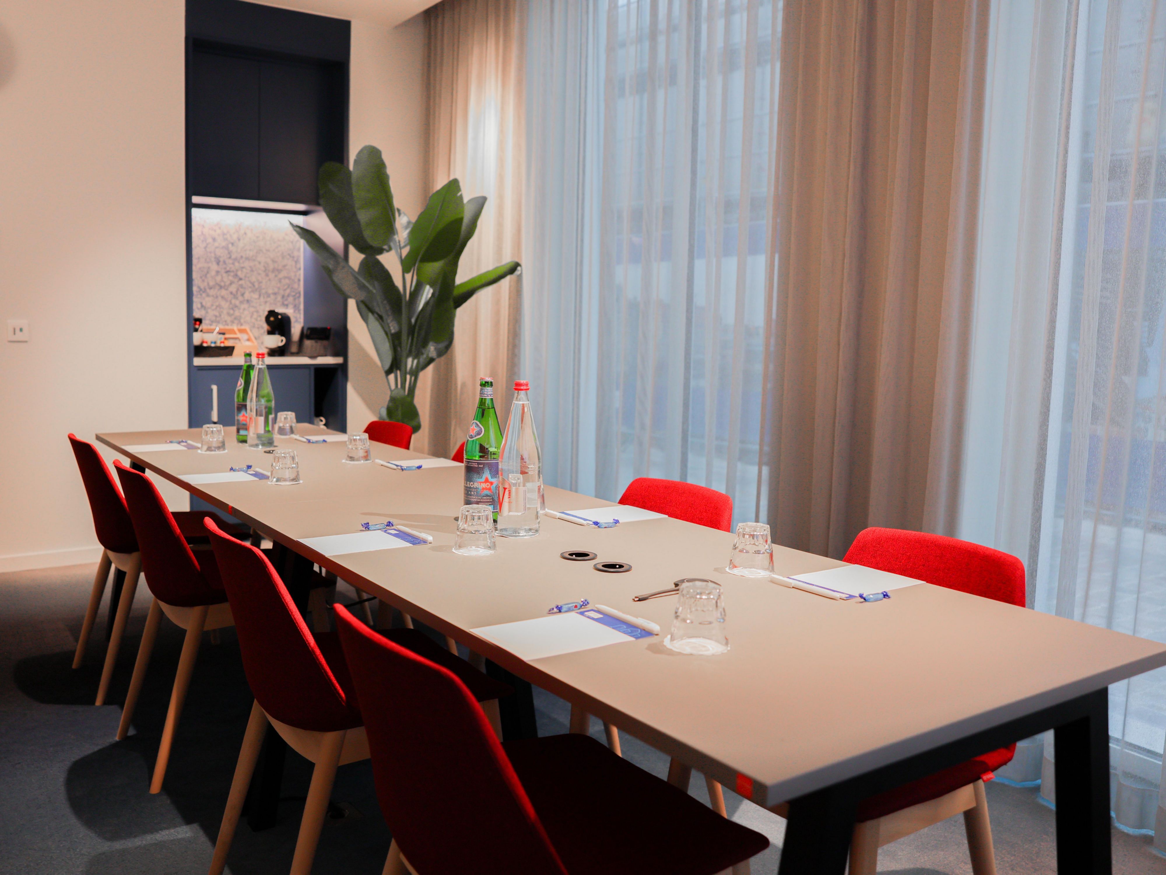 8 person meeting room with waters, red chairs, paer, pens, and large windows