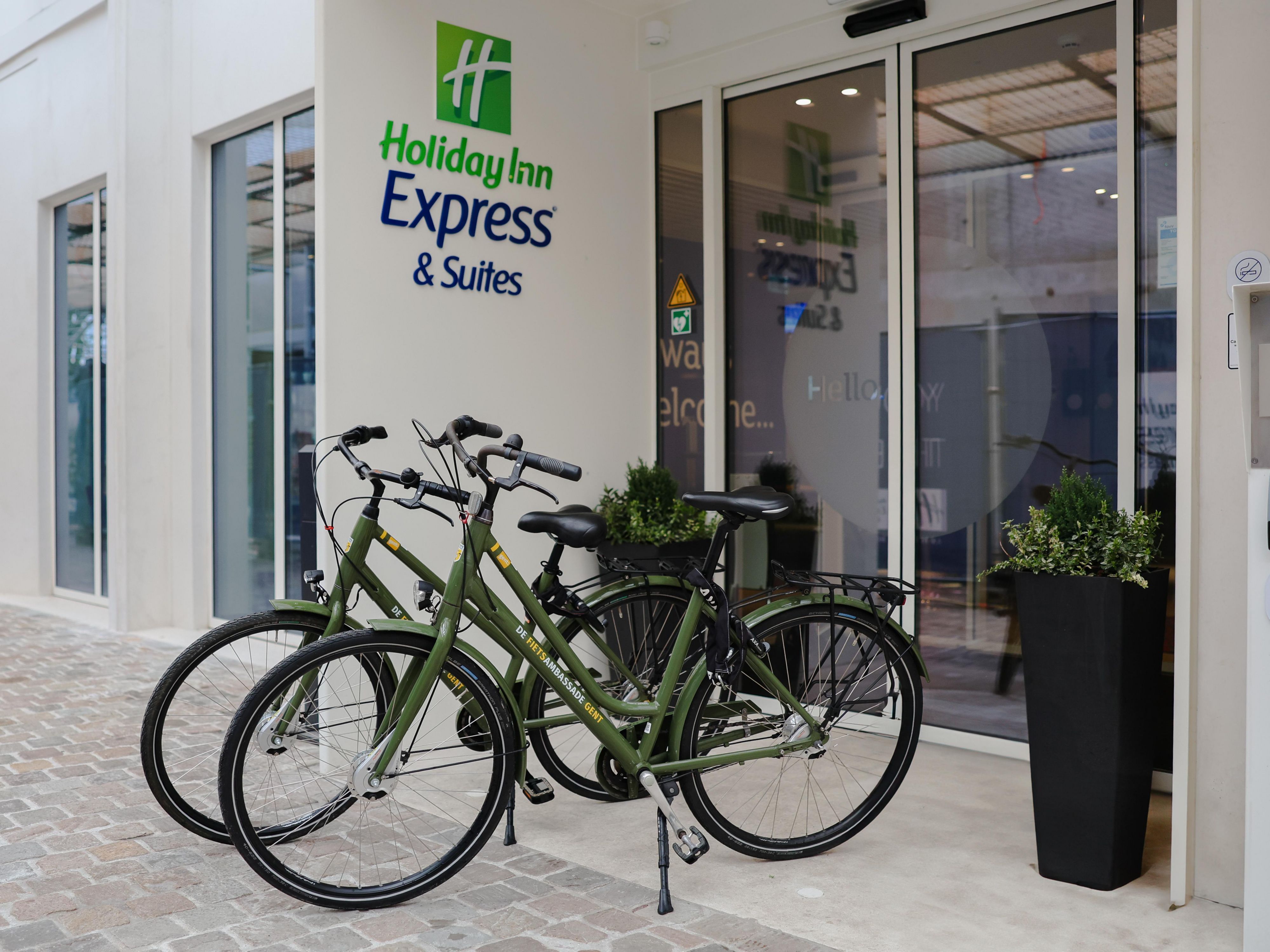 two bikes set outside the holiday inn express and suites ghent hotel entrance doors