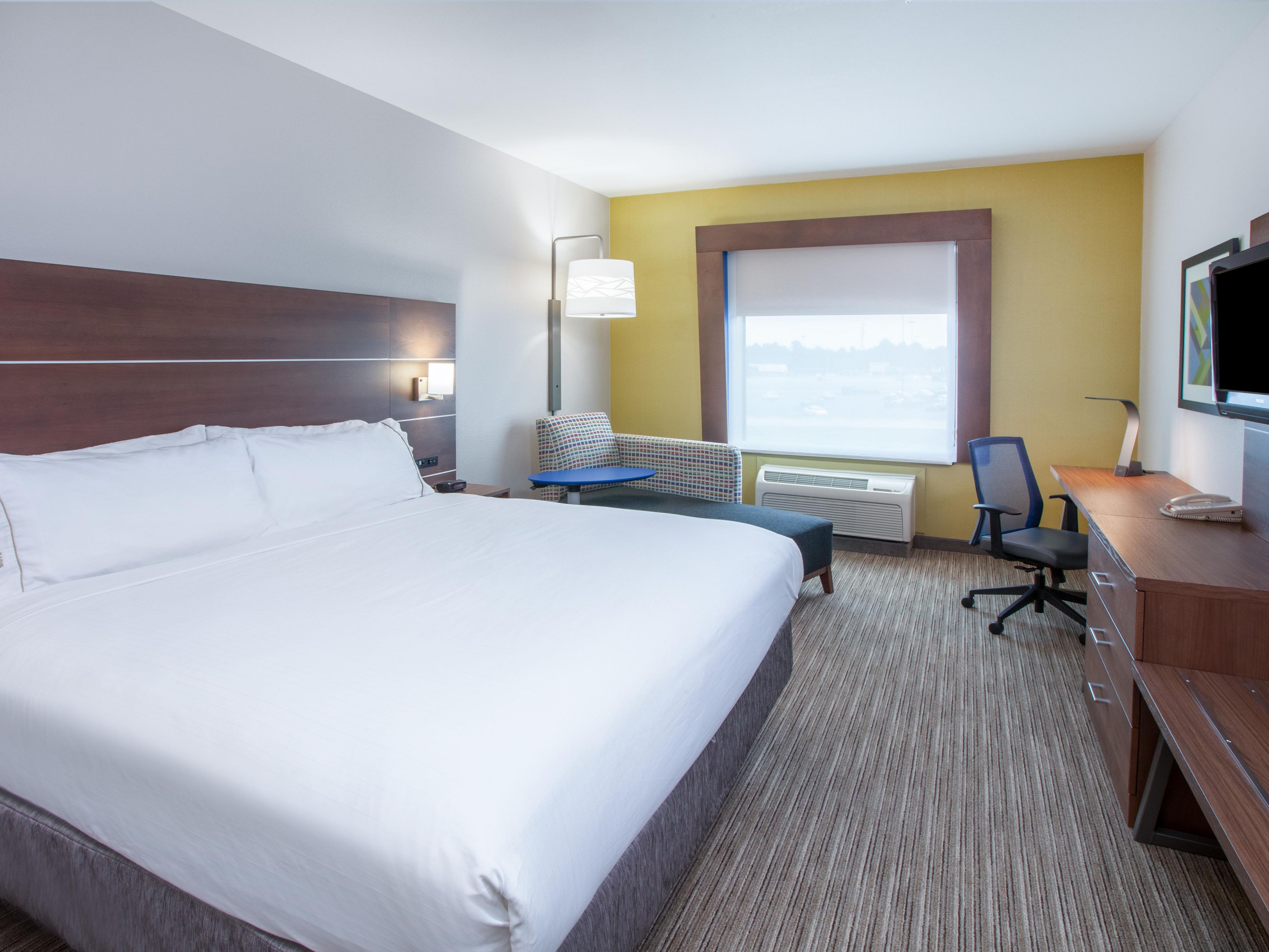 Spacious room with a king bed, workspace, and natural lighting.