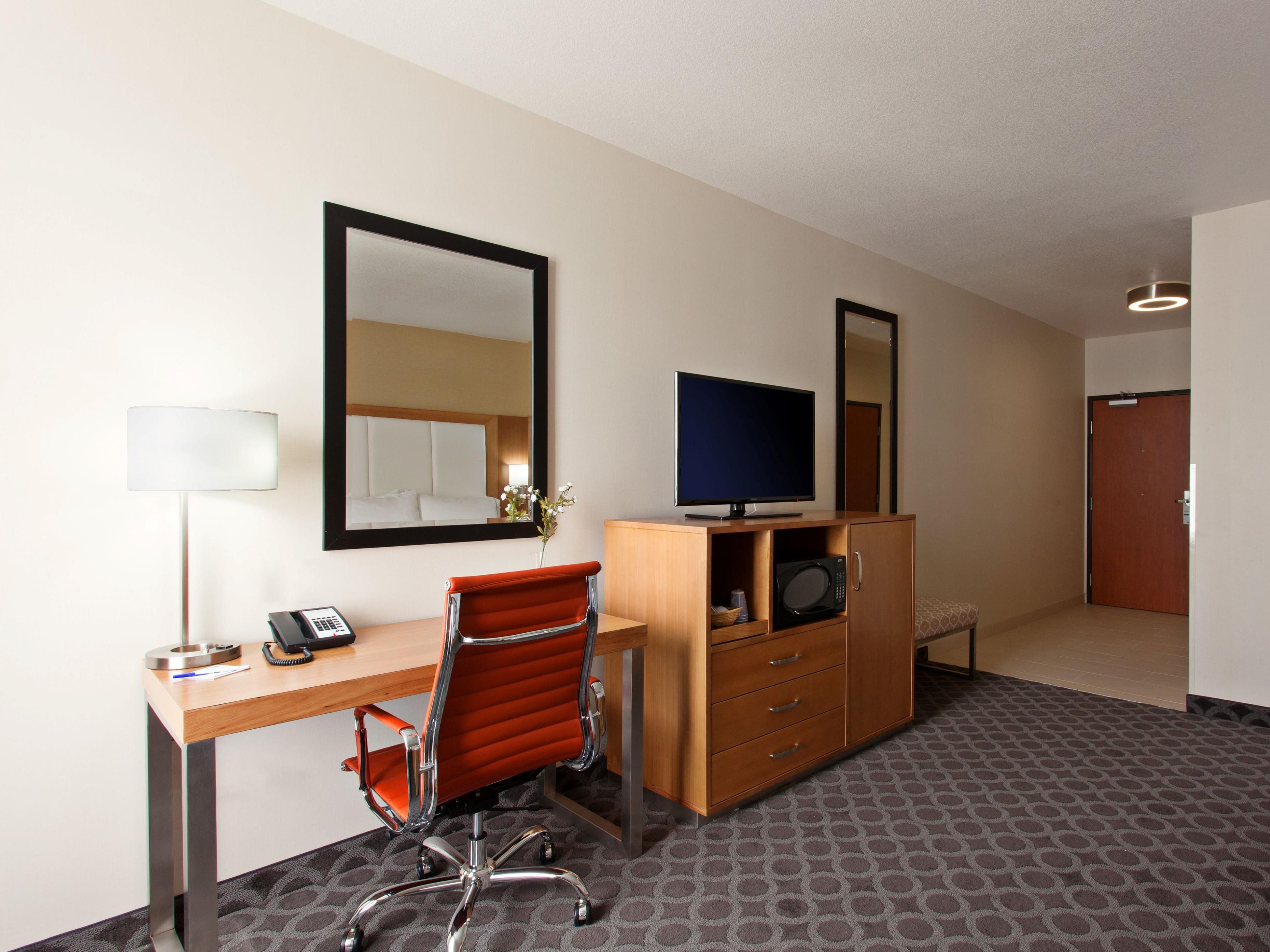 King bed guest room with well lit workspace and microwave.