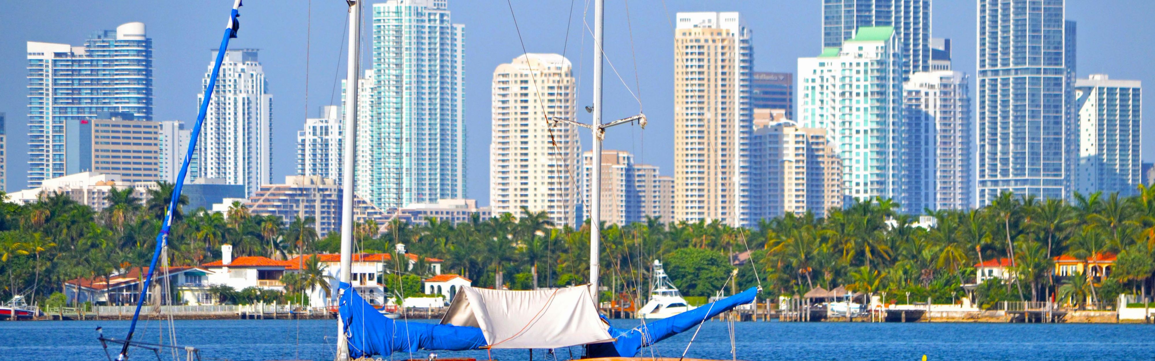 A sailboat on the ocean with a Miami cityscape backdrop.