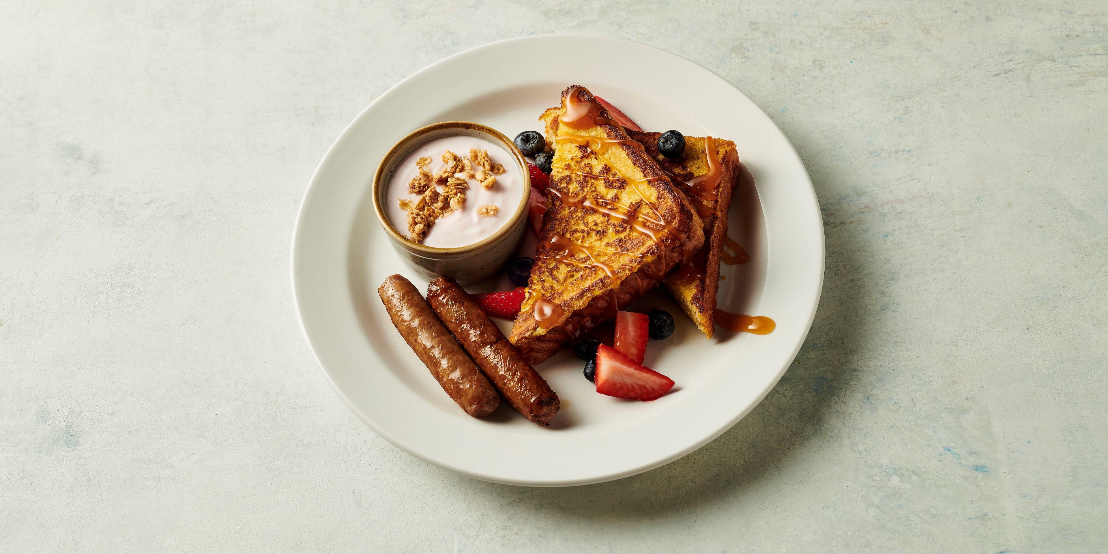 Decadent French toast with fresh fruit, yogurt, and sausage
