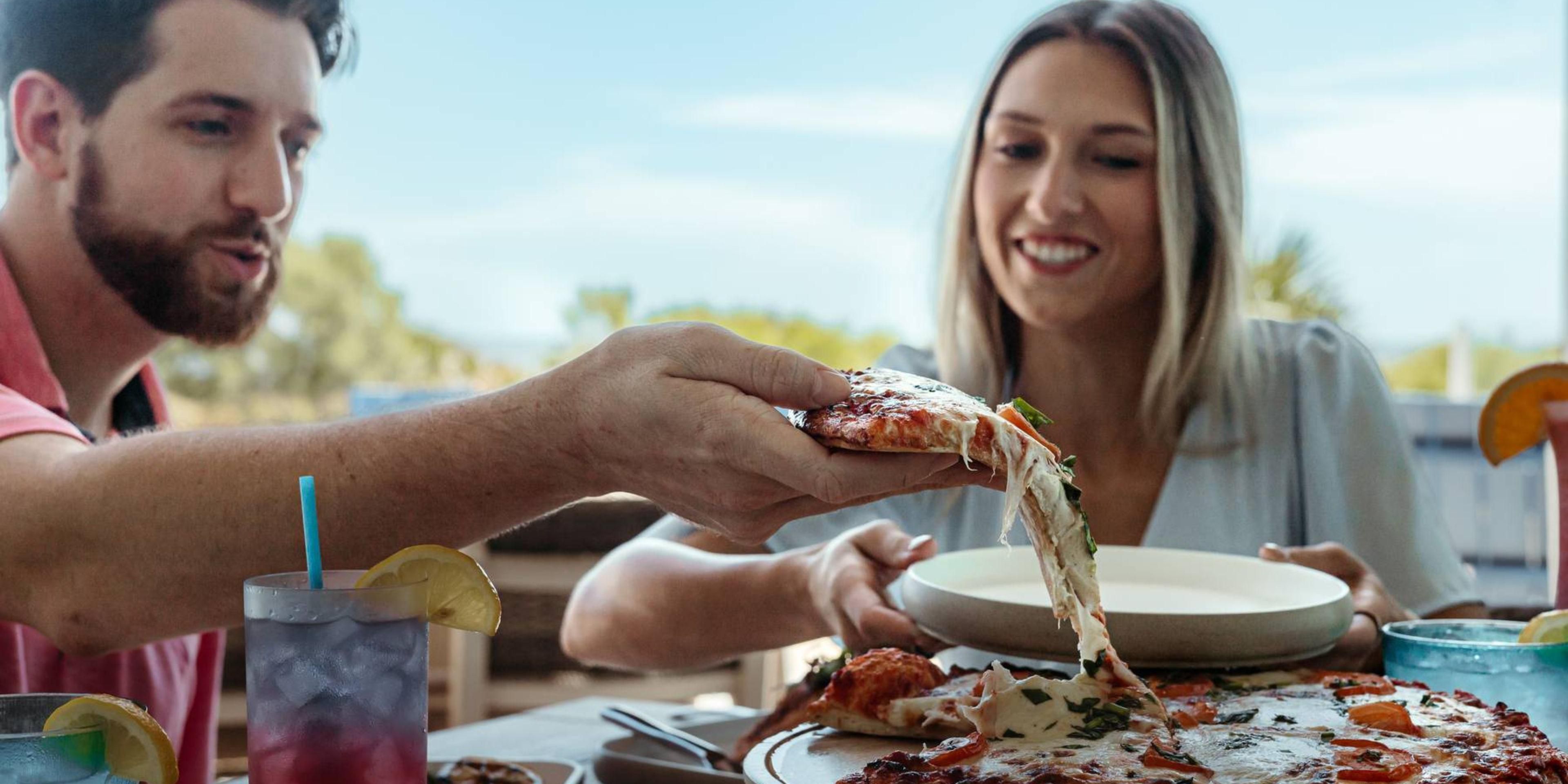 Man watching pizza pull and woman smiling