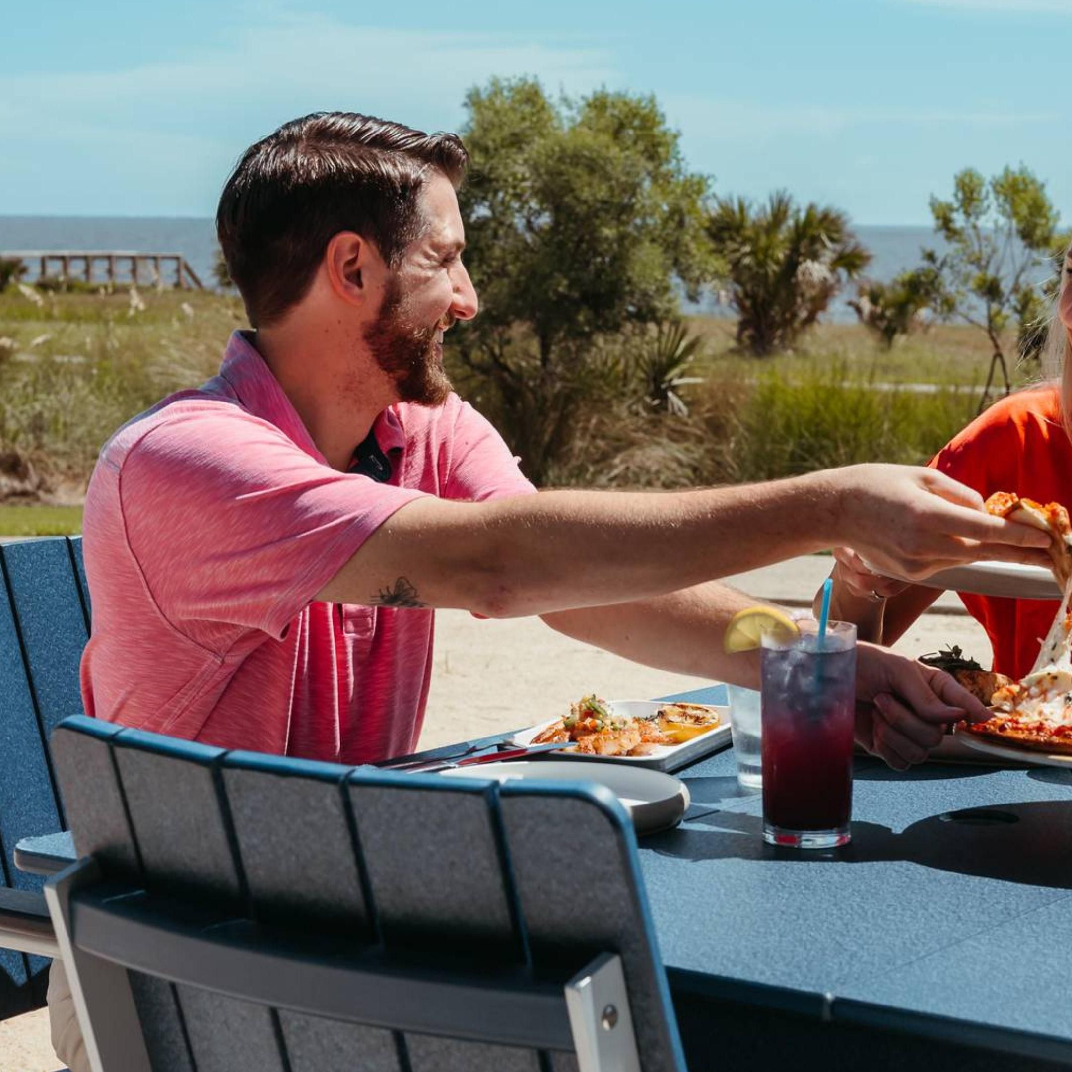 Man smiling and taking a piece of pizza