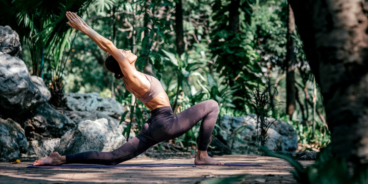 woman in a yoga pose surrounded by tropical foliage