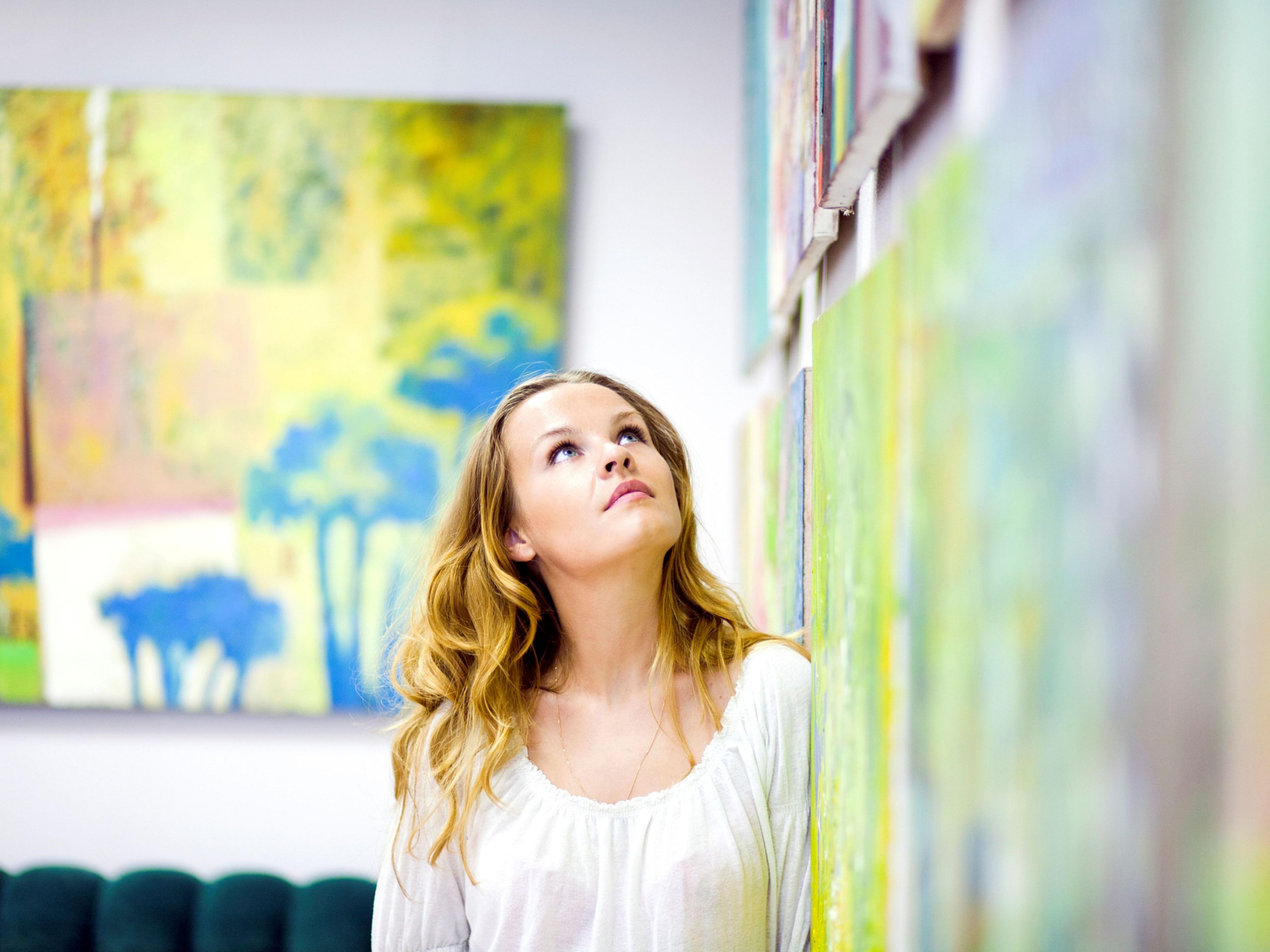  person gazes at colorful artwork on a gallery wall. 