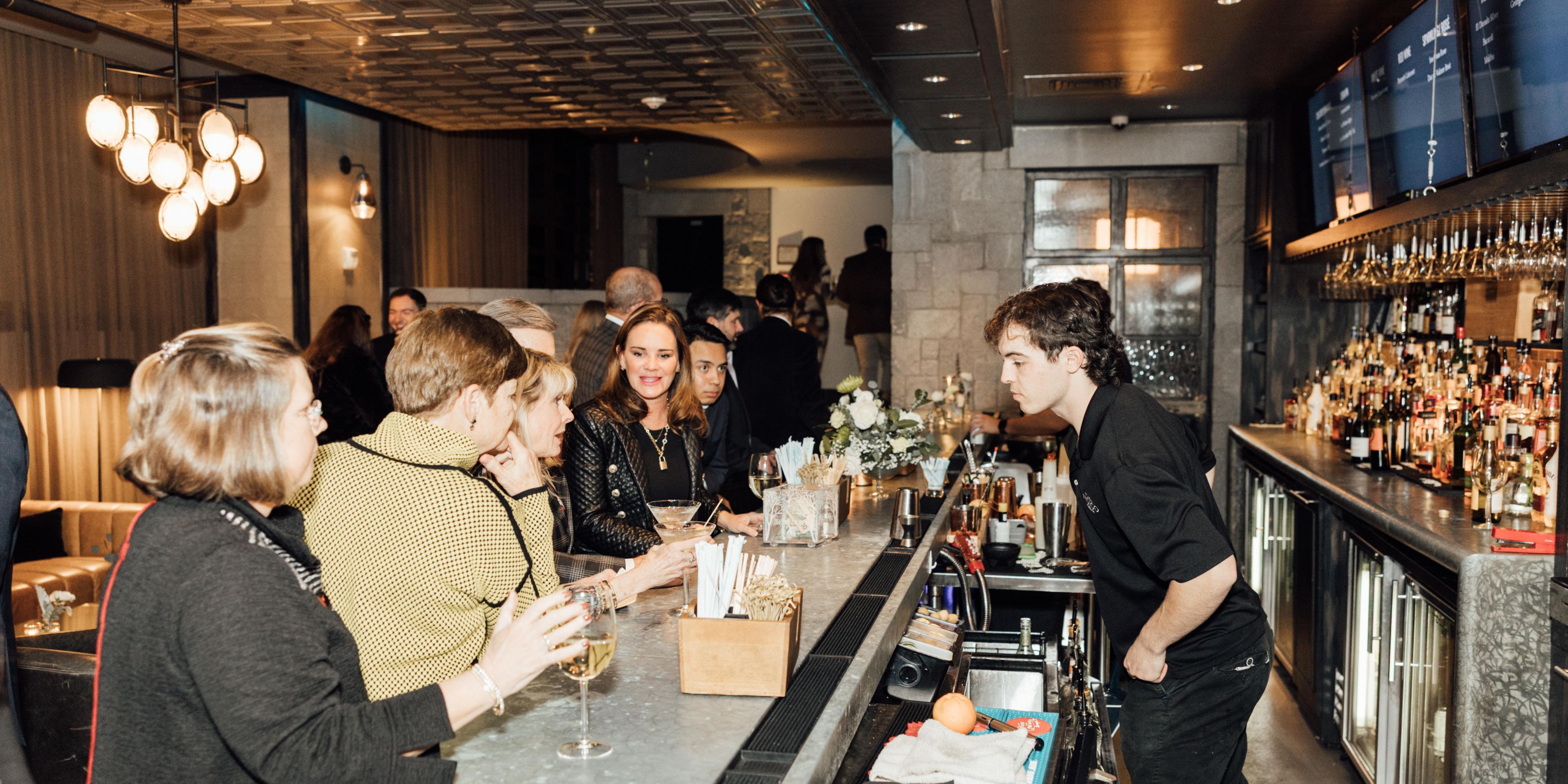 Bartender serves guests at a stylish bar during an event.