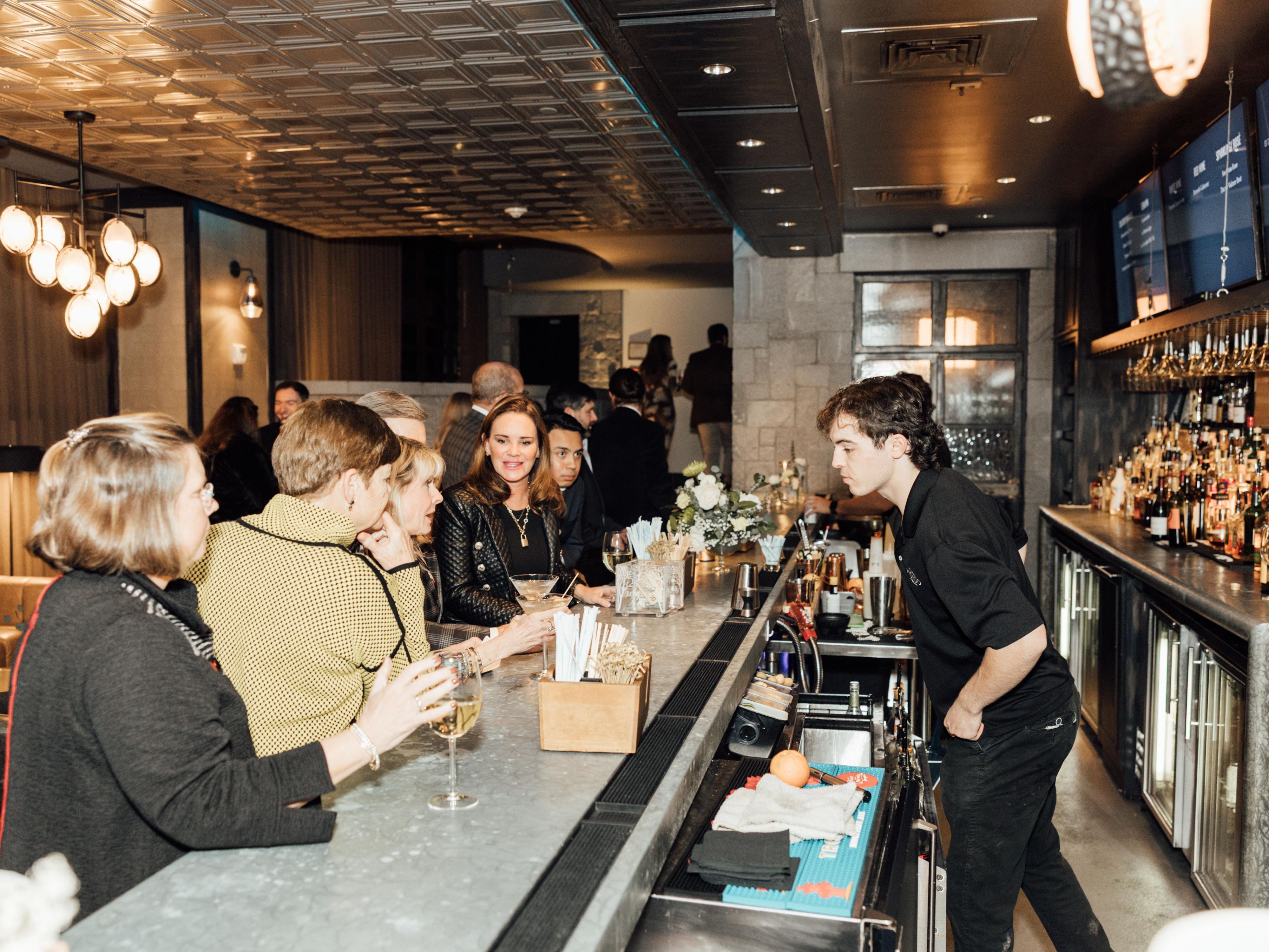 Bartender serves guests at a stylish bar during an event.