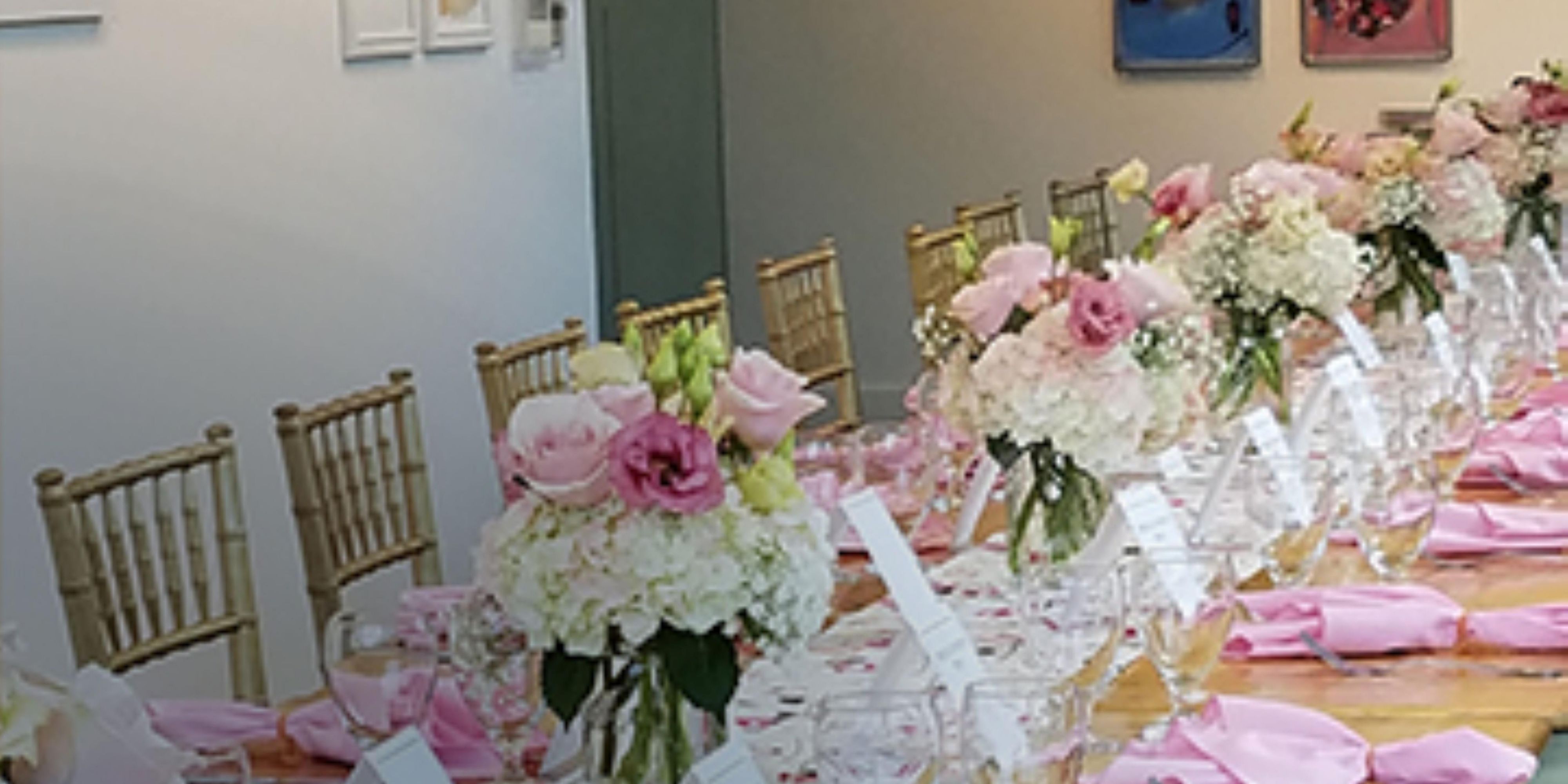 Wooden table with pink napkins, place settings, and flowers.