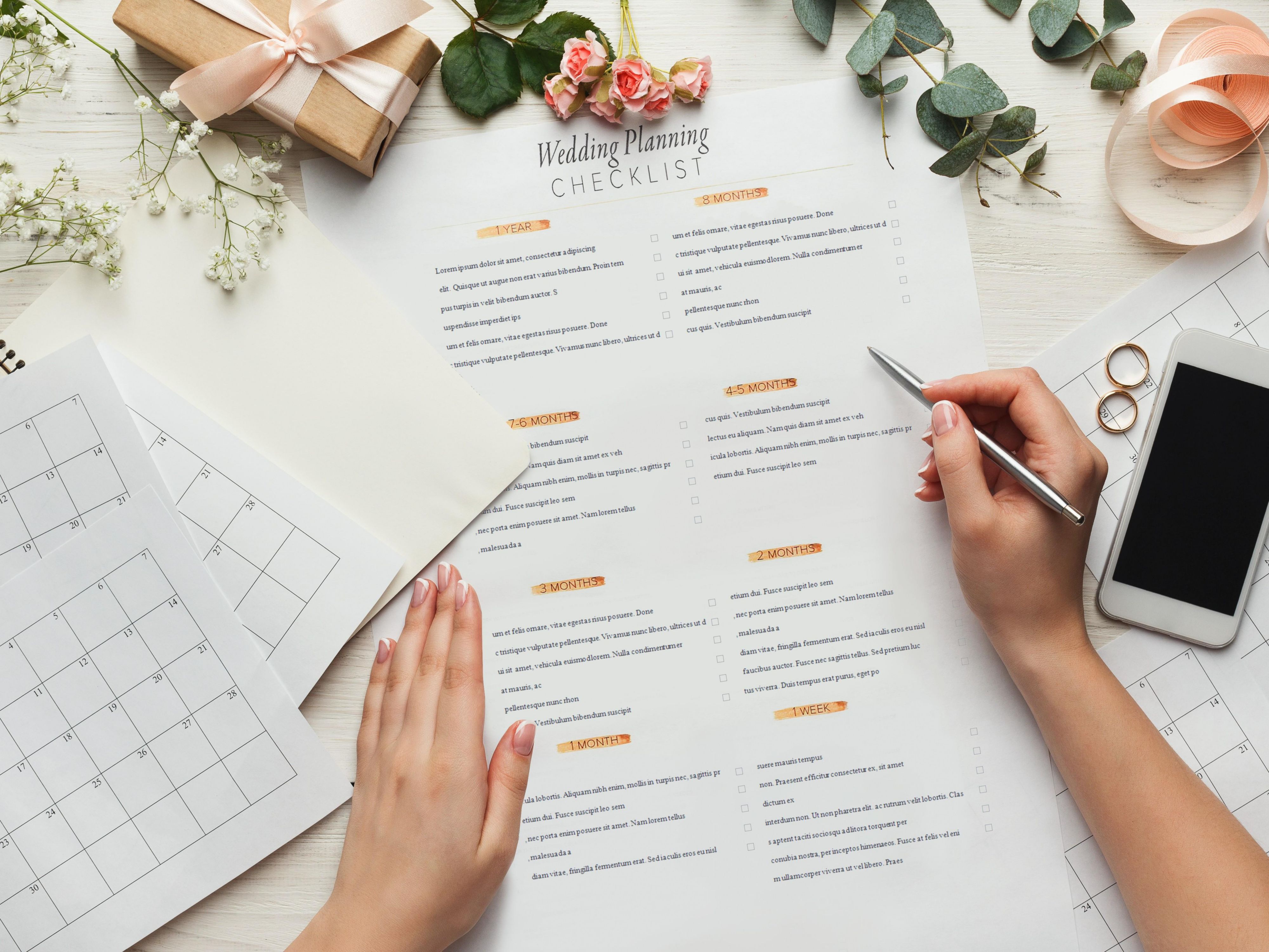 A person reviews a wedding checklist with rings and flowers.