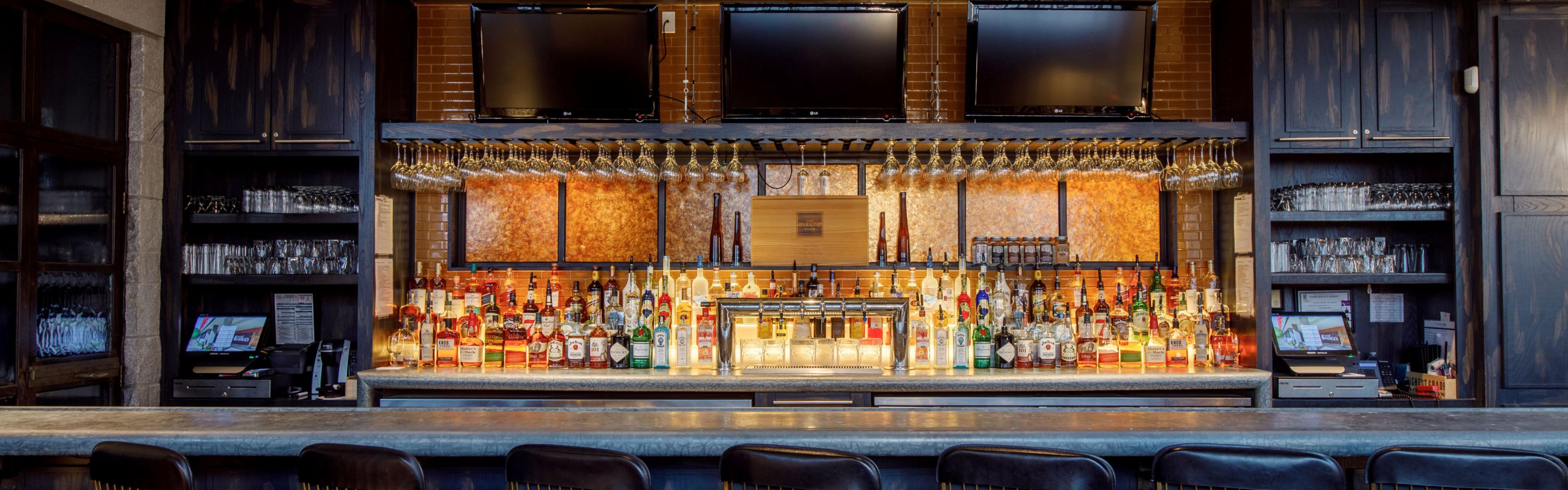 Warmly lit bar with wood cabinetry and gold barstools.