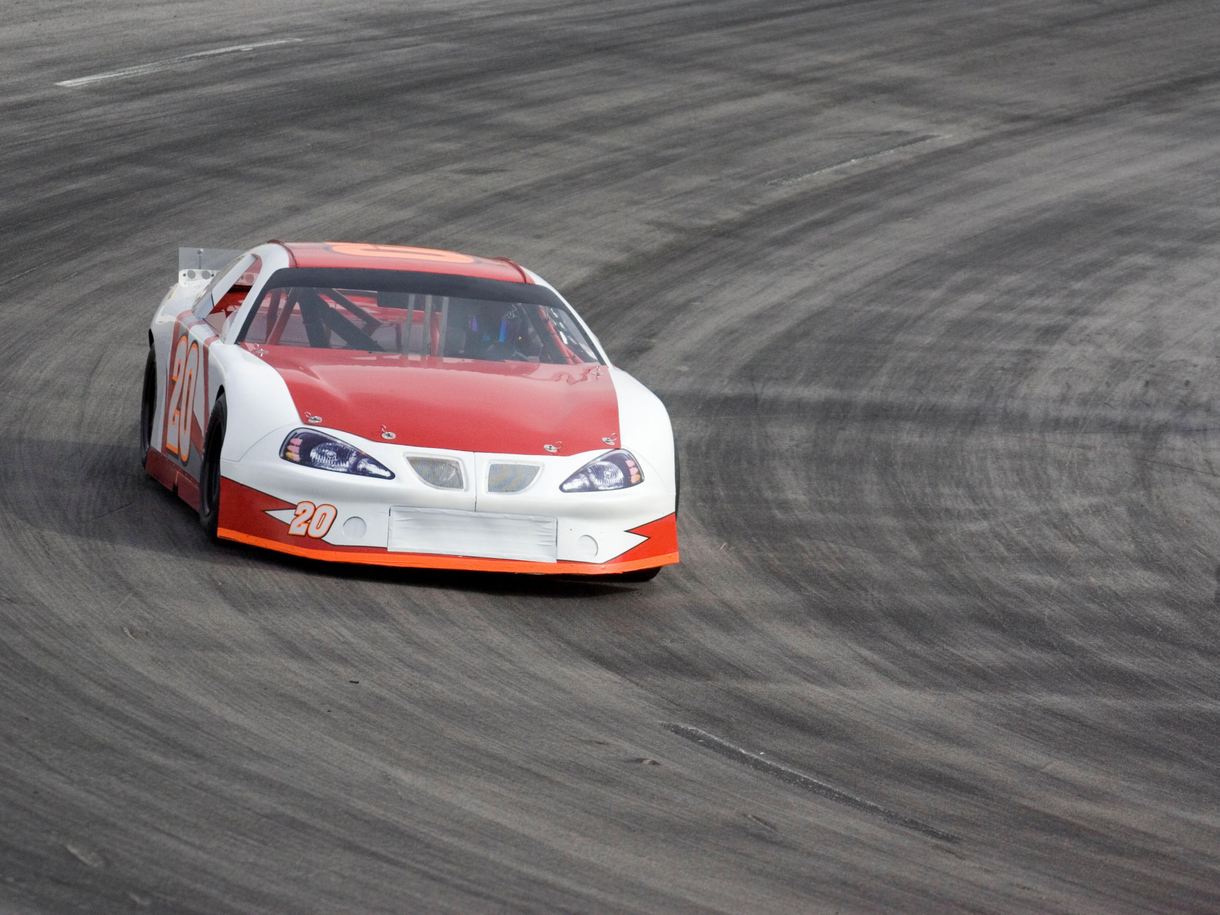 Red and white race car speeding around a curved track