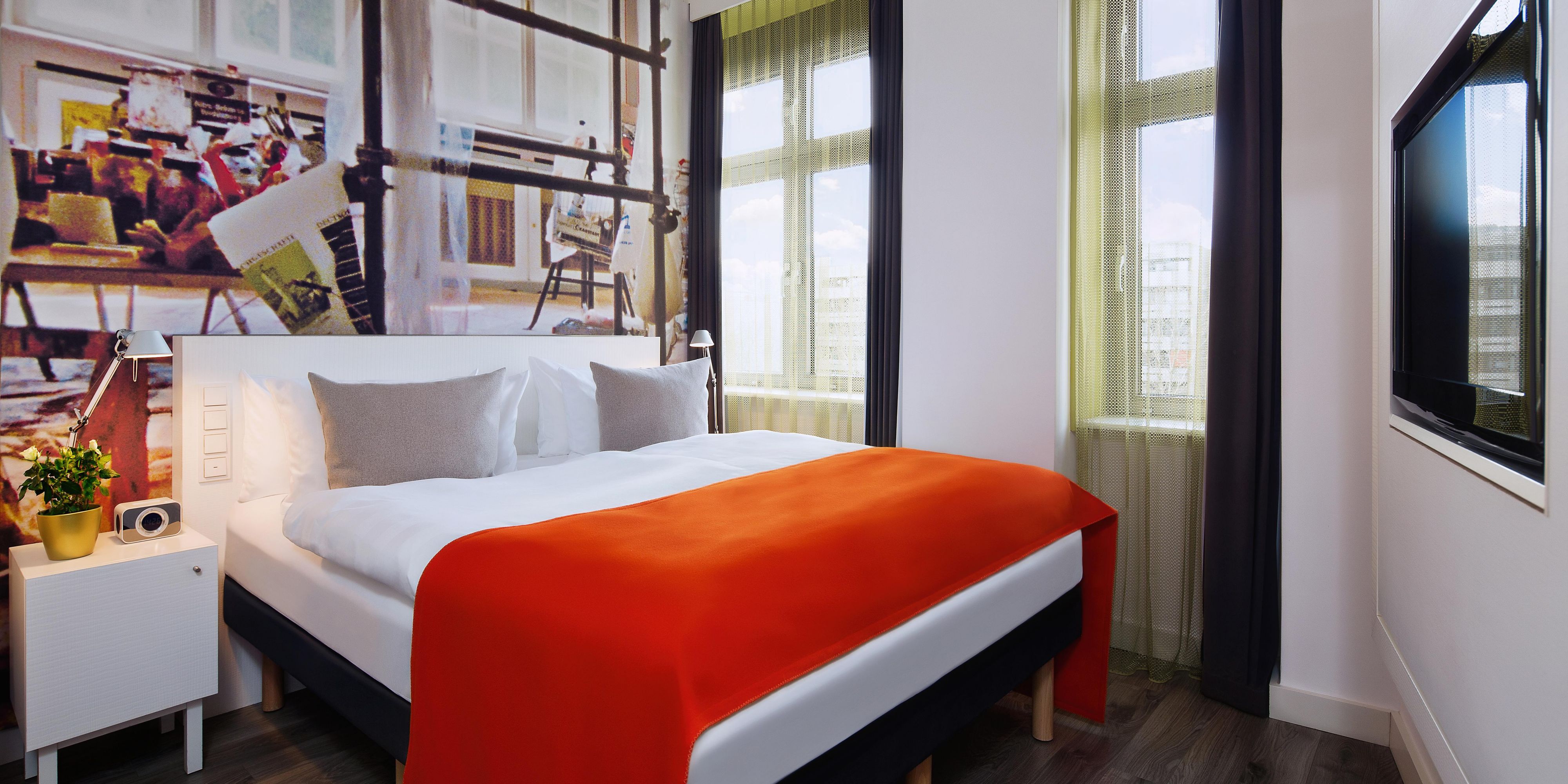 A guest room with a double bed and stylish wallpaper.