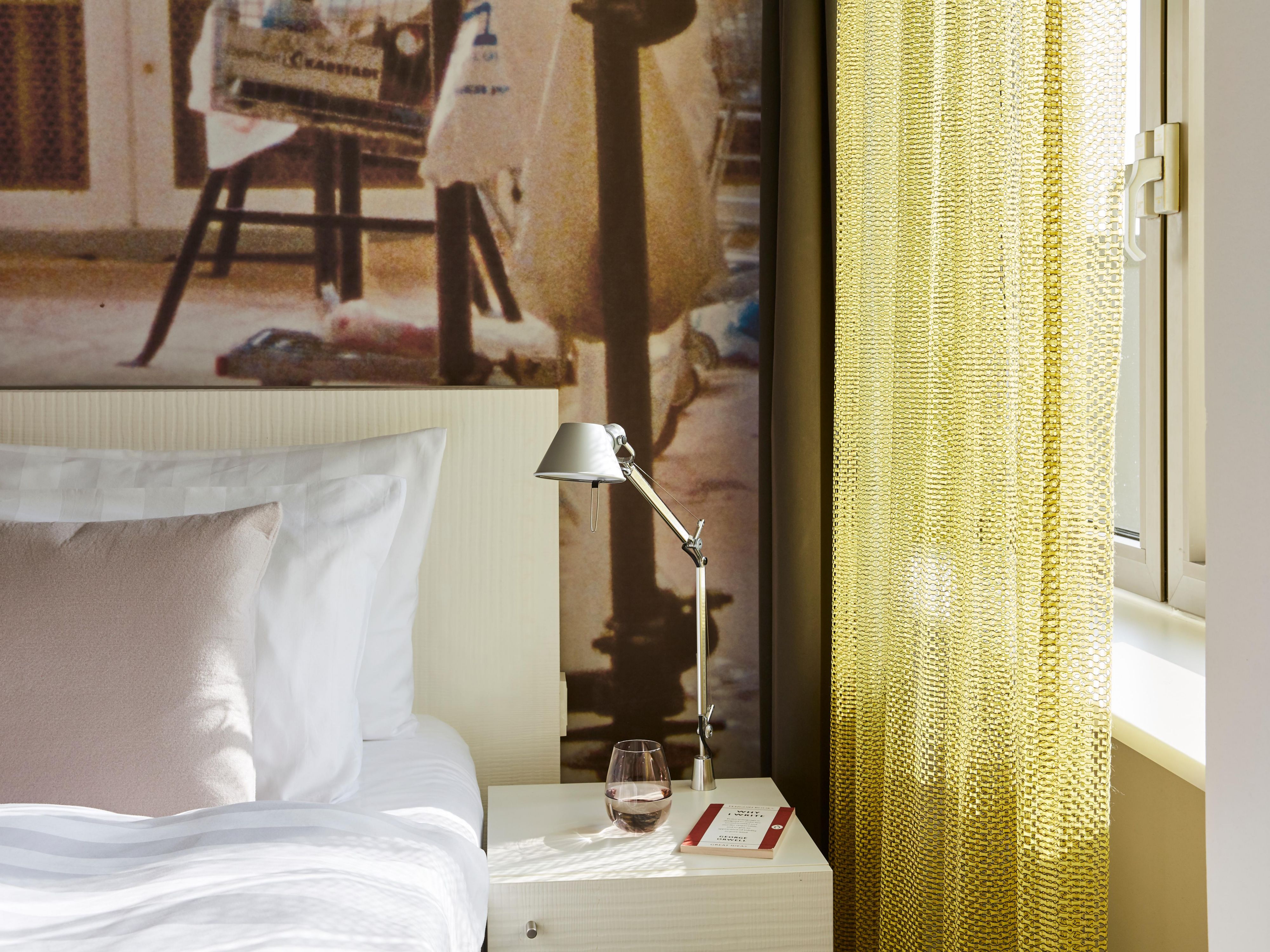 A guest room with a double bed and funky wall print.