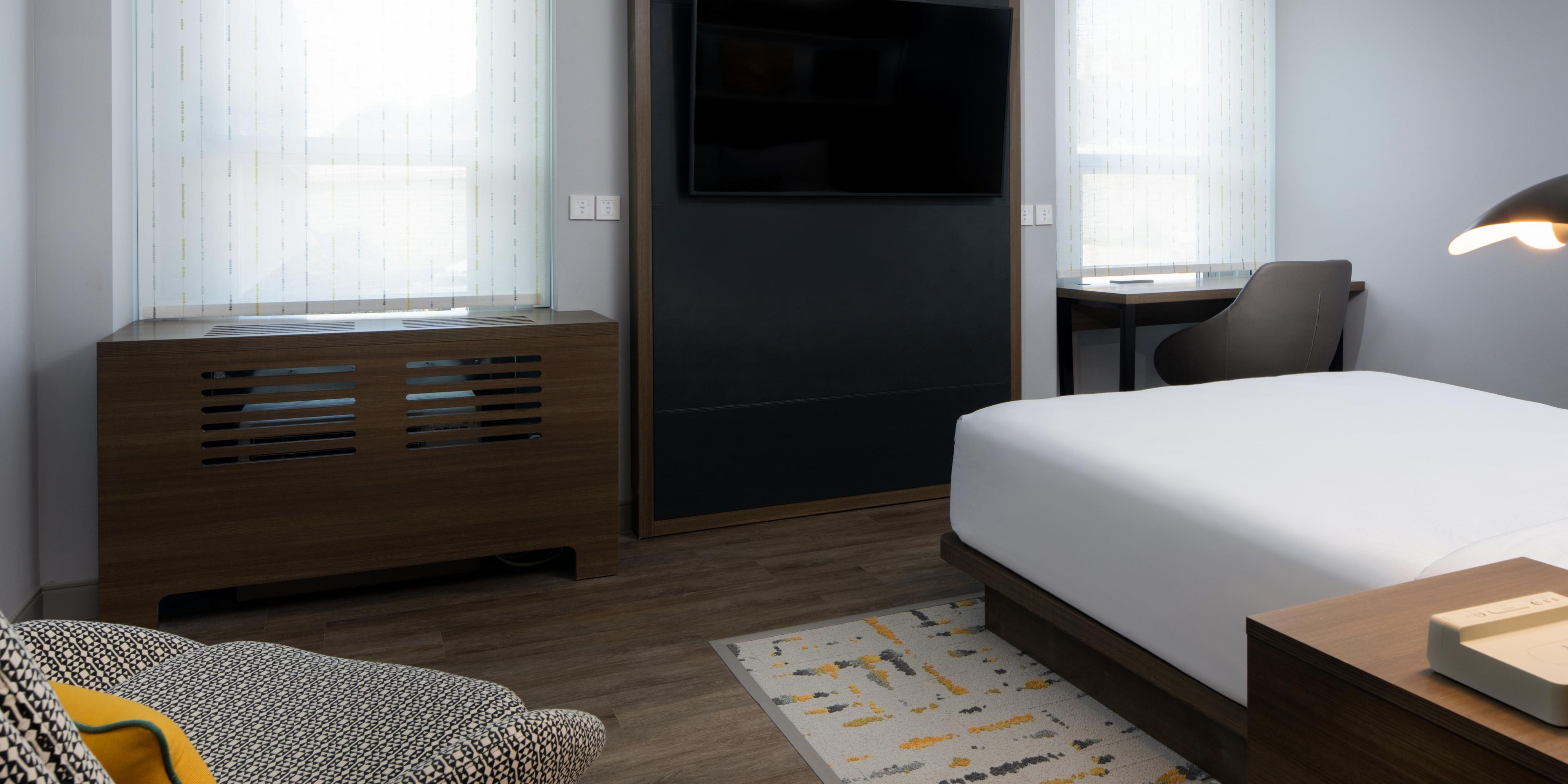 Queen Guest Room featuring large windows, desk, and mounted tv!