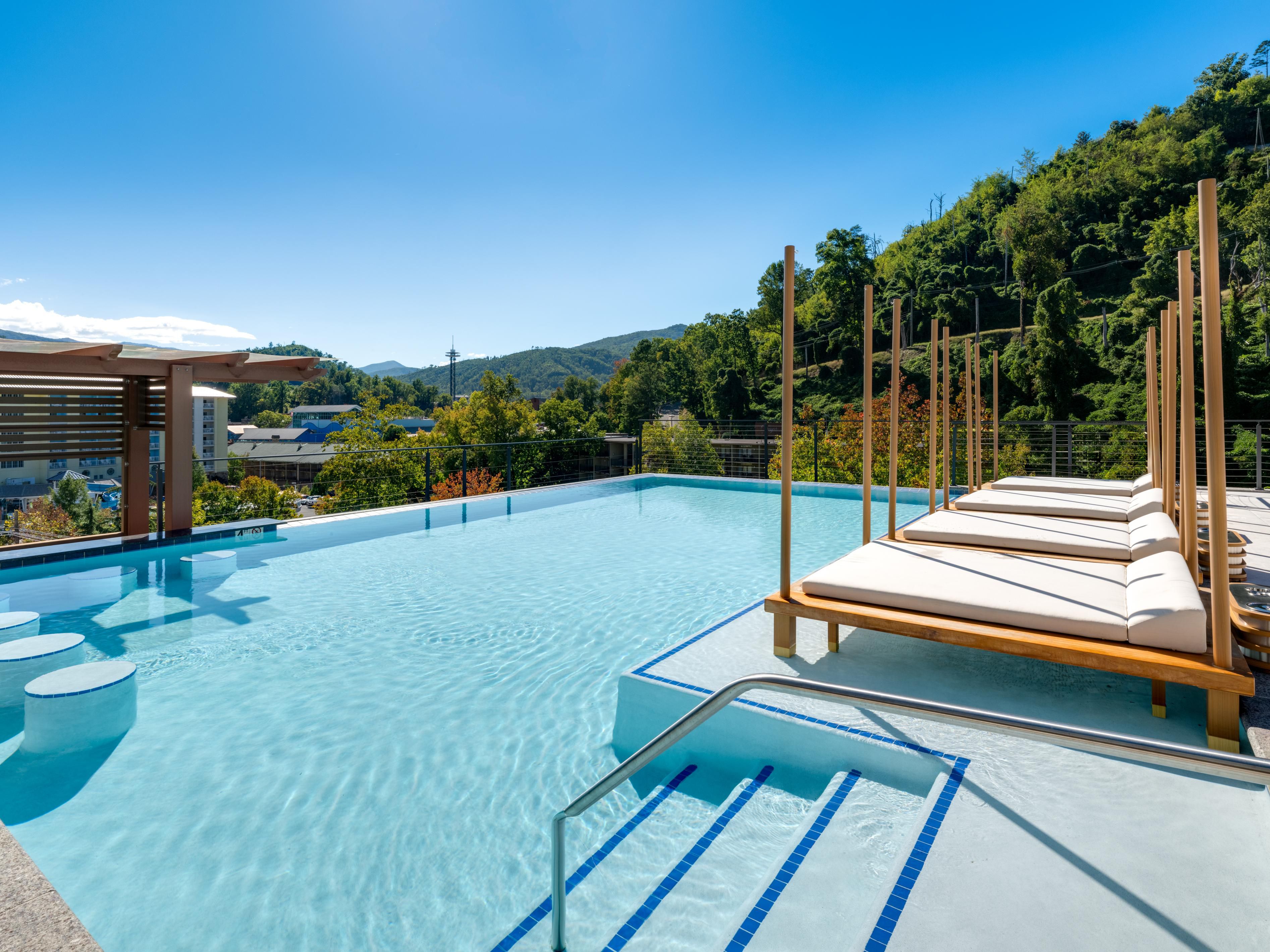 Rooftop infinity pool with seating and views.