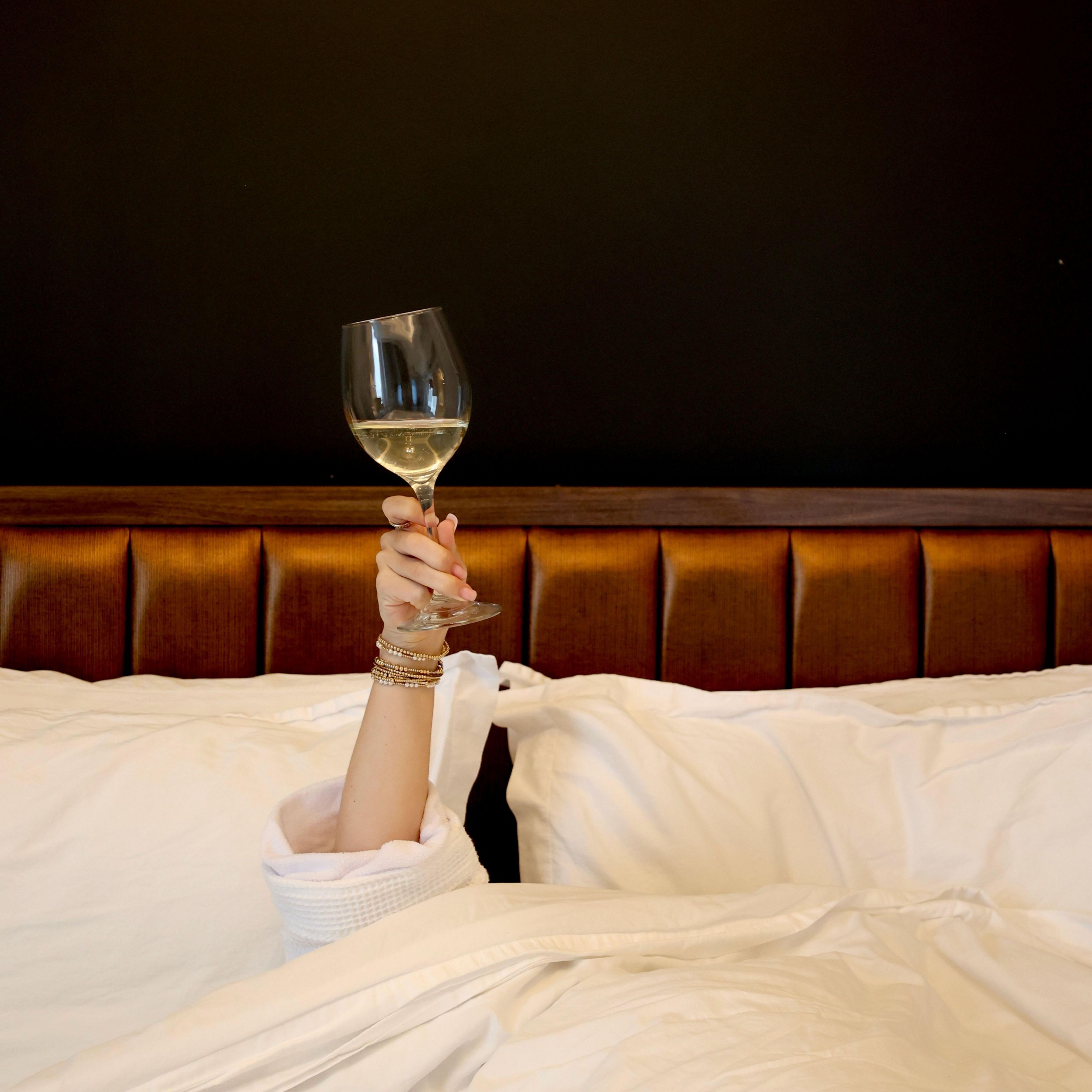Guest enjoying a glass of wine while relaxing in bed