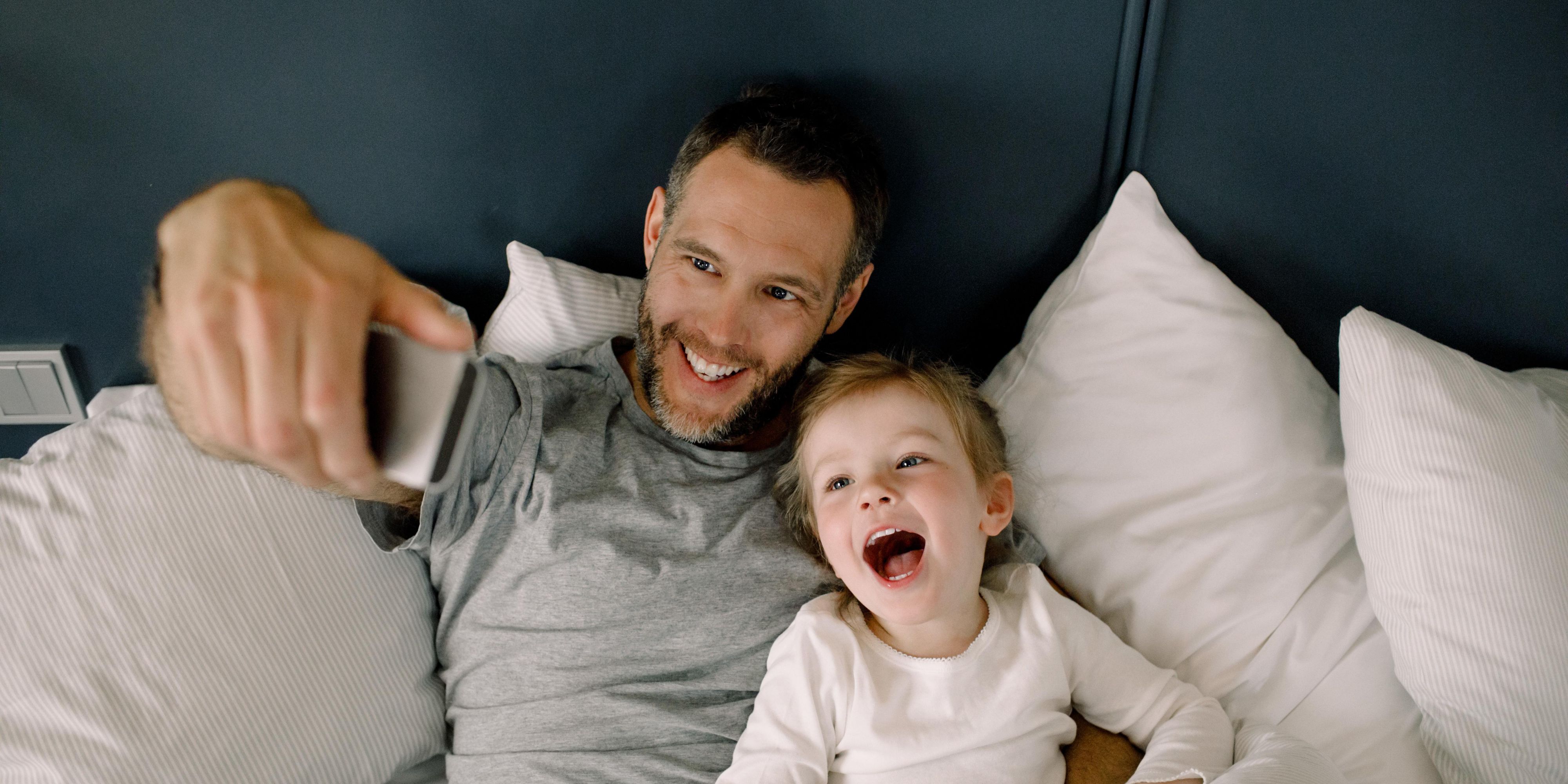 dad and son taking a selfie in hotel guest bed, smiling