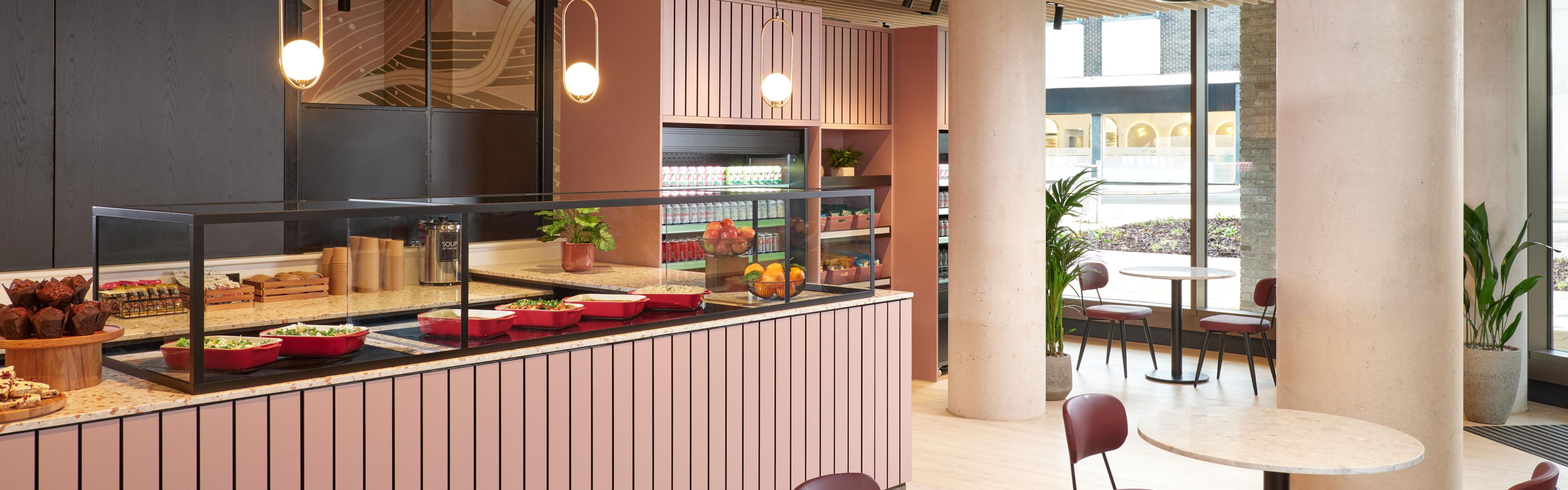 cafe area with pink interior, plenty of seating, and large windows creating a brightly-lit room