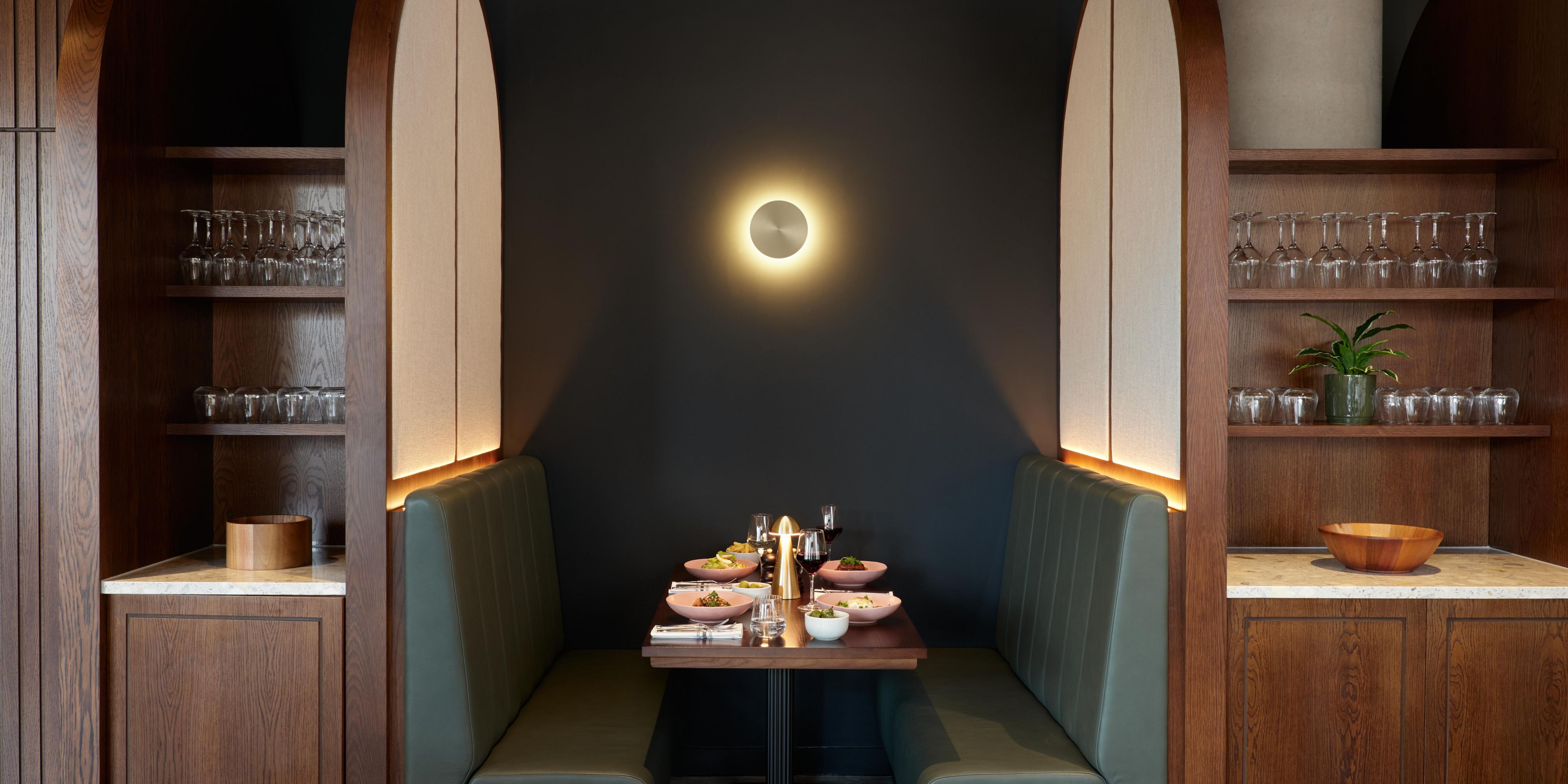green coloured booth with dim lighting and dishes on the table
