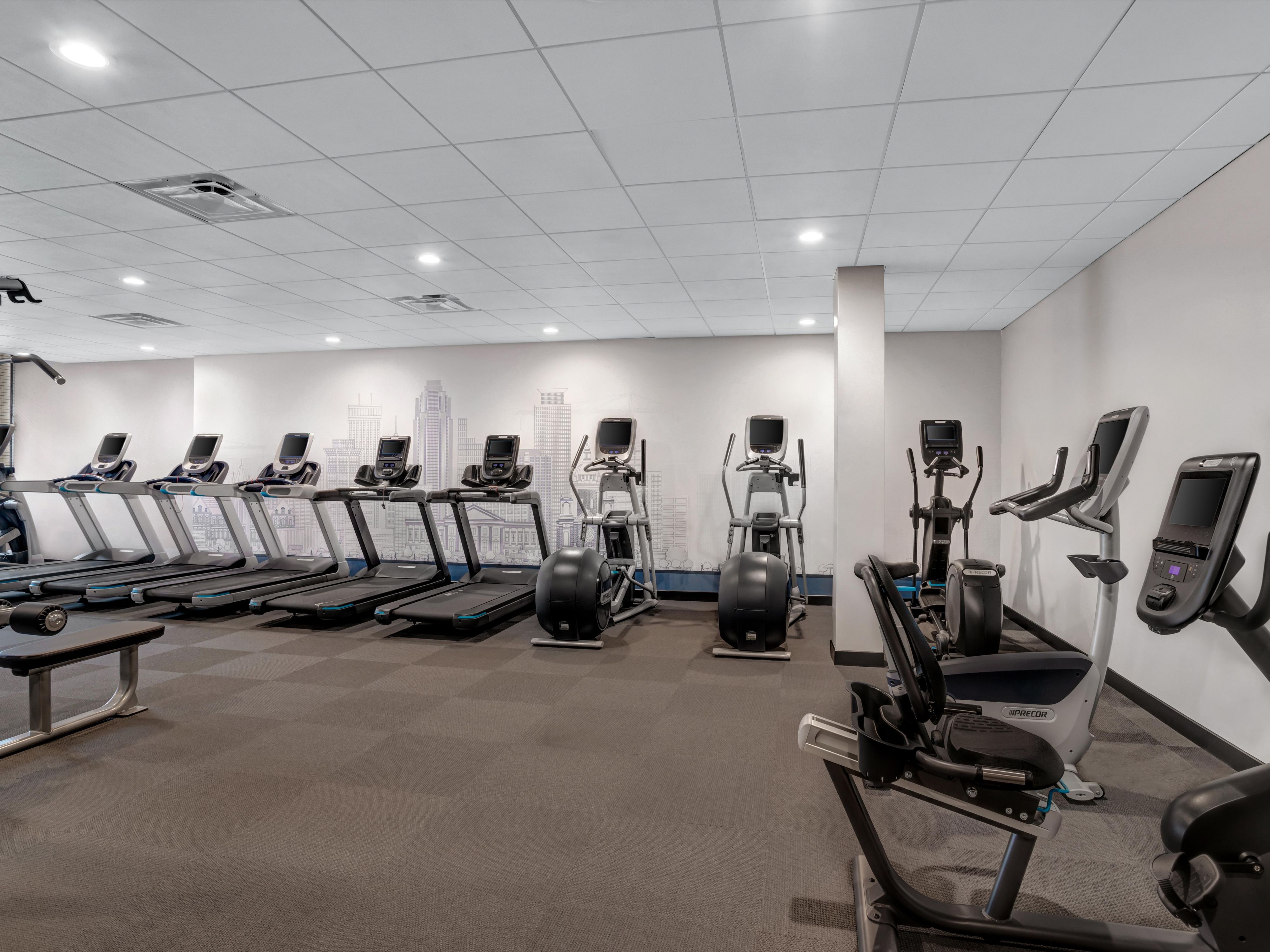Large fitness studio featuring ample cardio equipment and Peloton