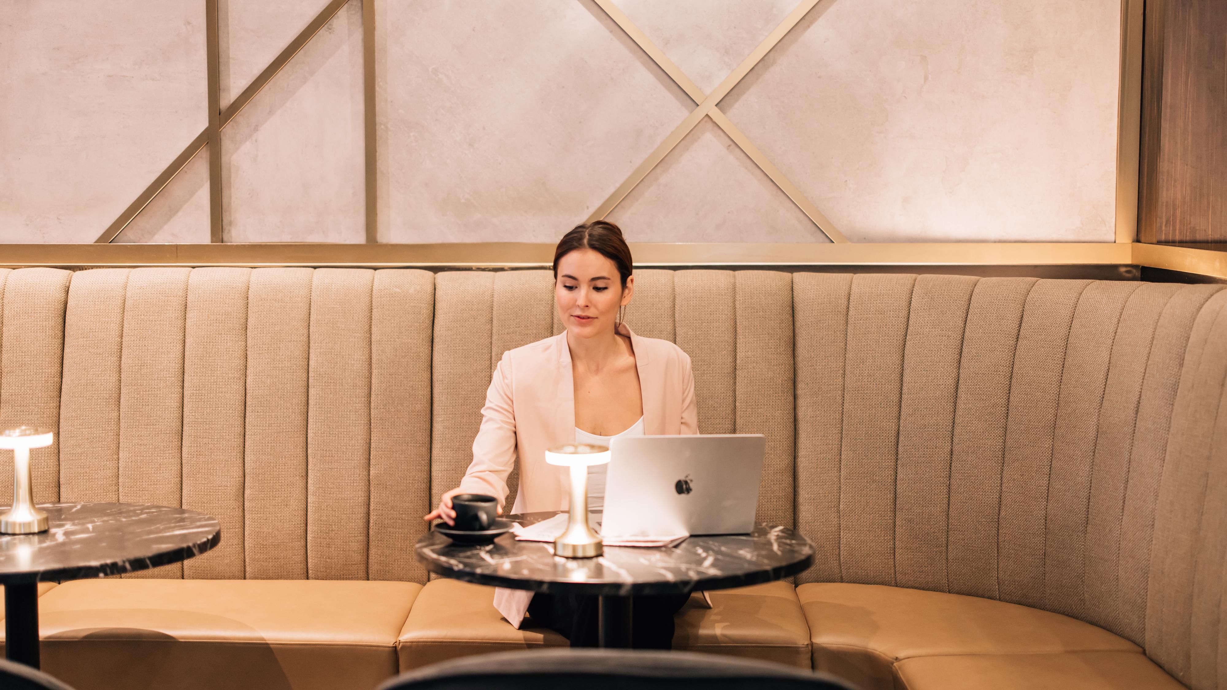 Woman sitting in a cafe with a laptop and coffee.
