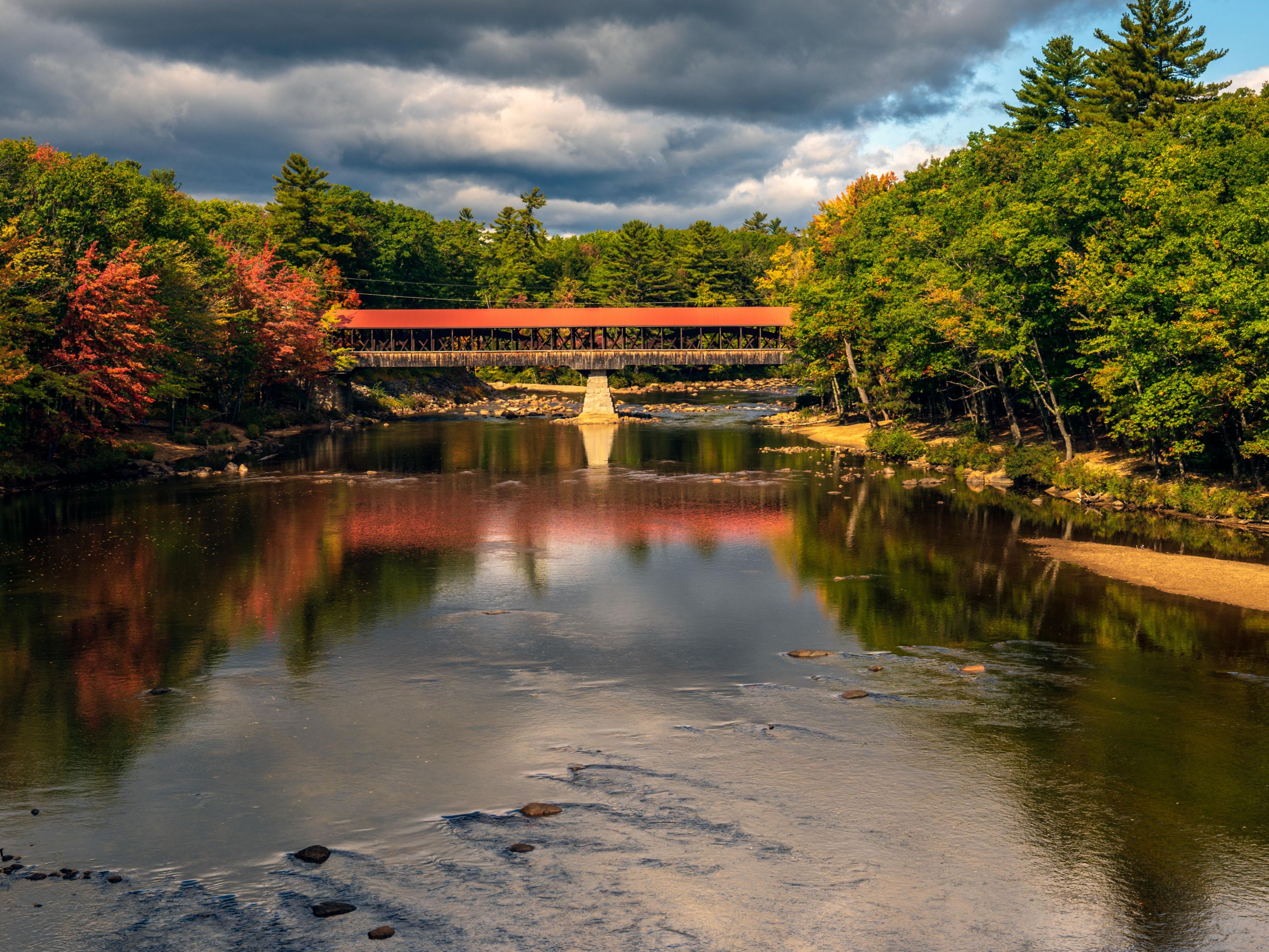 Historic covered bridge framed by stunning mountain scenery.