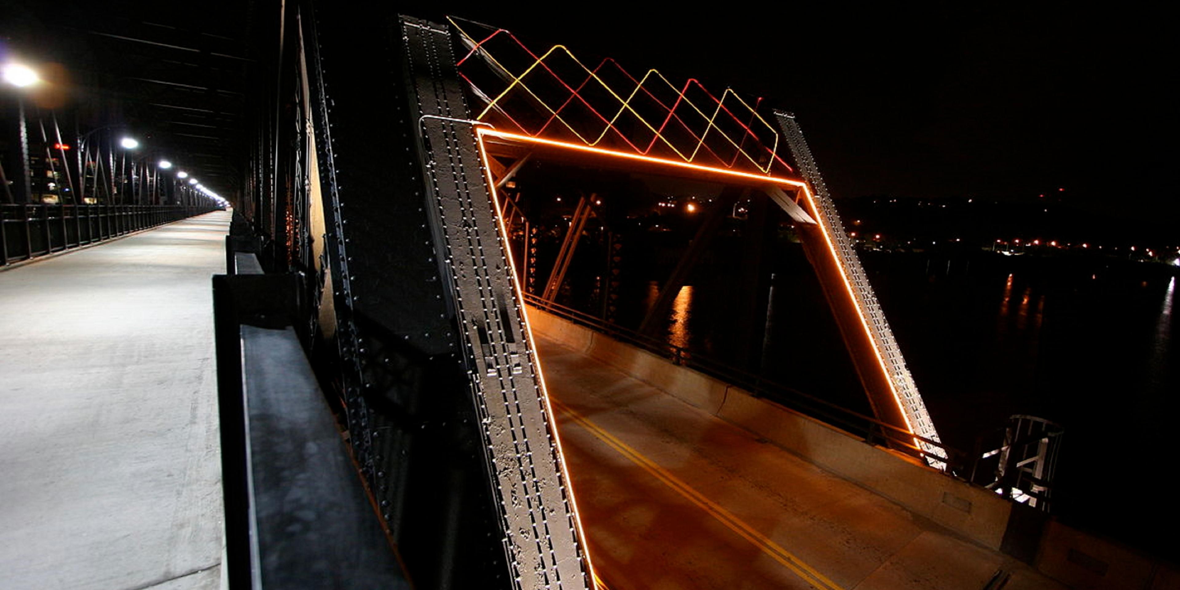 Pitts Hot Metal Bridge at night lit up by Hotel Indigo Pitts Univ