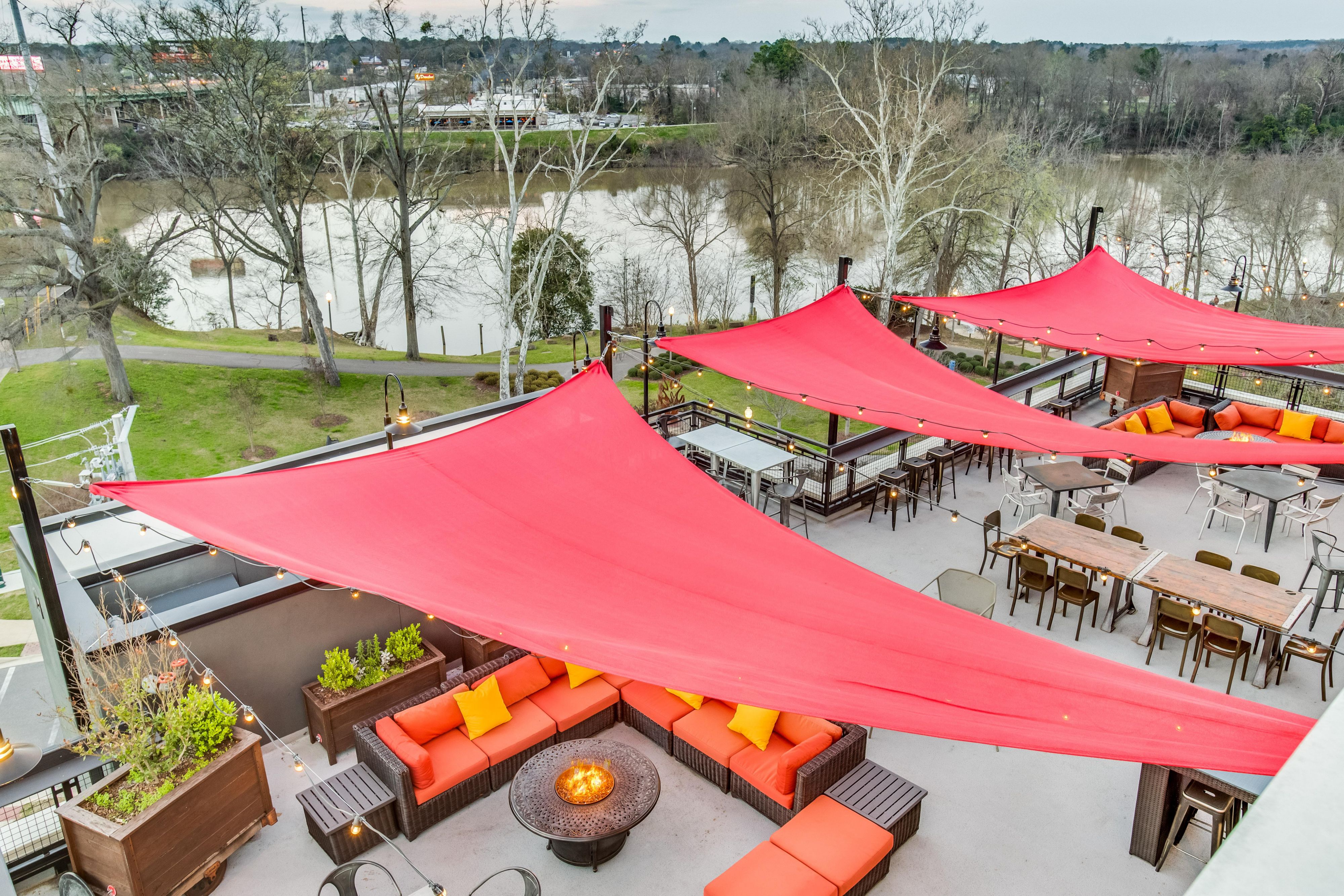 The Lookout is located atop the Hotel Indigo Tuscaloosa Downtown with stunning views of the Black Warrior River and downtown. Unwind with a cocktail near the fire pits or enjoy conversational seating with friends during happy hour. The Lookout is close enough to the Tuscaloosa Amphitheater that you can hear the live music from the rooftop.