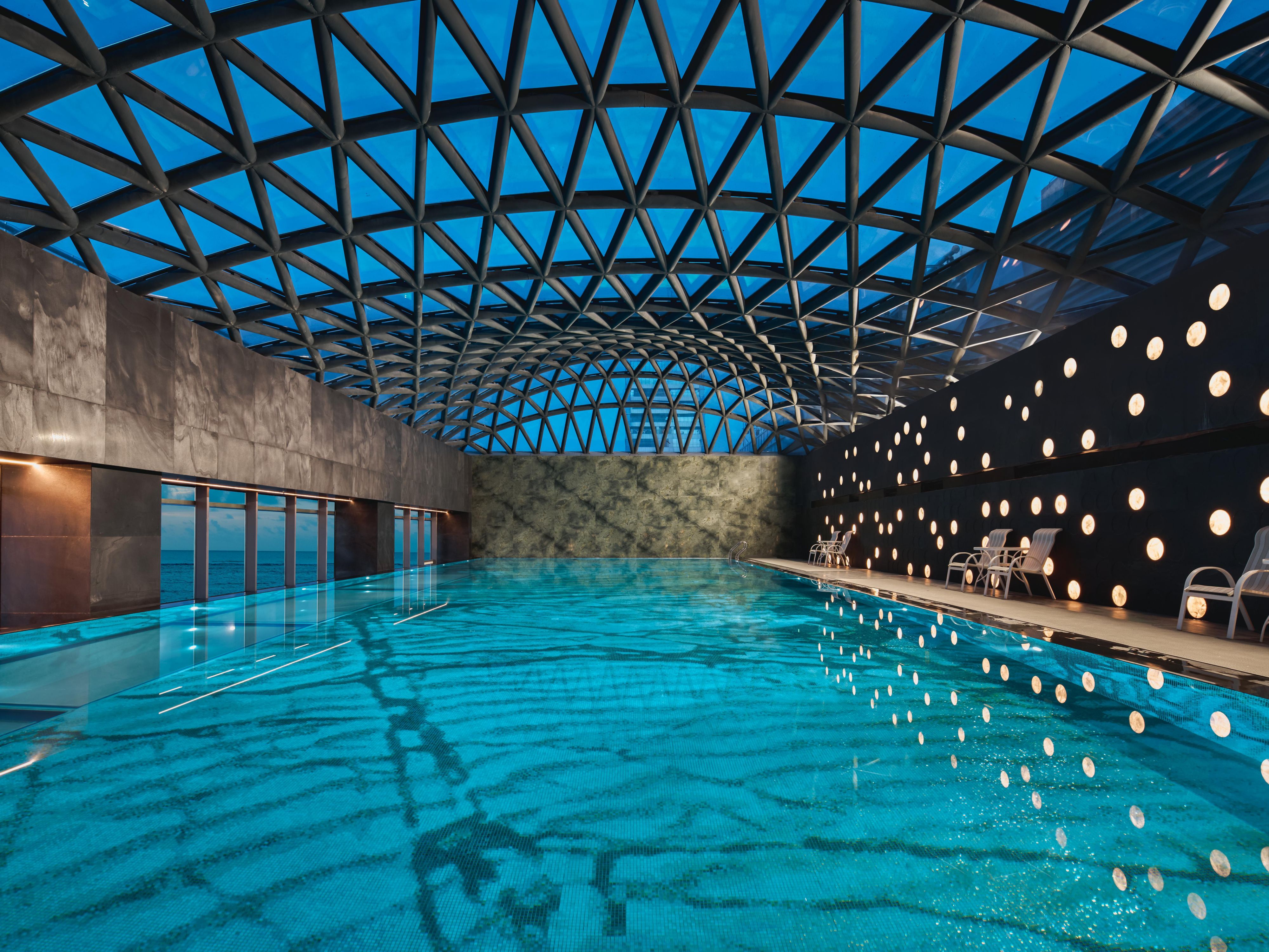 Pool is 25 x 10 meters, with a depth of 1.4 meters. Water temperature is maintained at 26-28°C to ensure optimal comfort, while you gaze at sweeping views of the surrounding landscape where the sky meets the sea. Inspired by the ocean, the water surface has the appearance of a mirror, while the bottom of the pool is as colorful as the seabed.
