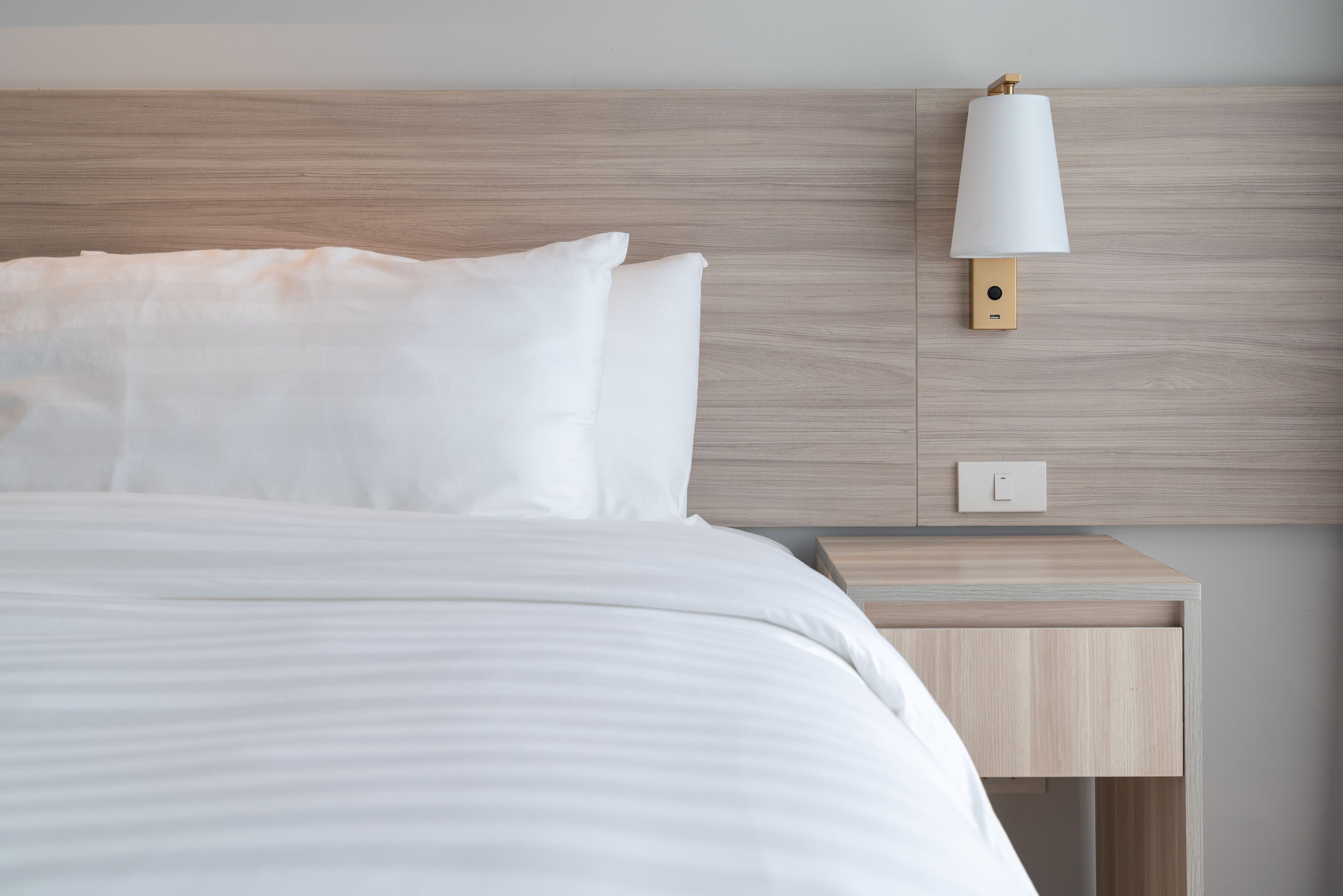 Hotel room with bed, wall sconce and nightstand