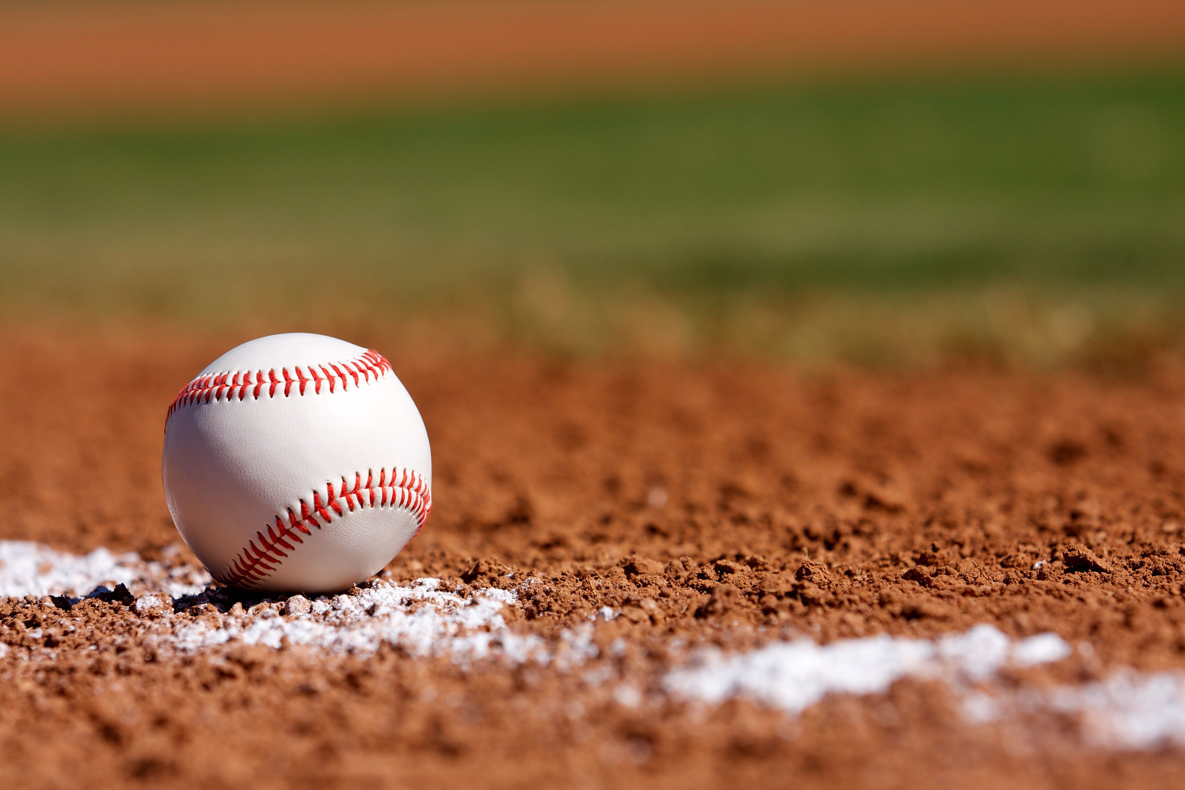 Baseball resting on infield dirt near a foul line