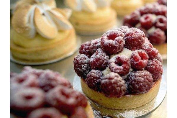 Individual berry desserts topped with fresh raspberries and powdered sugar.