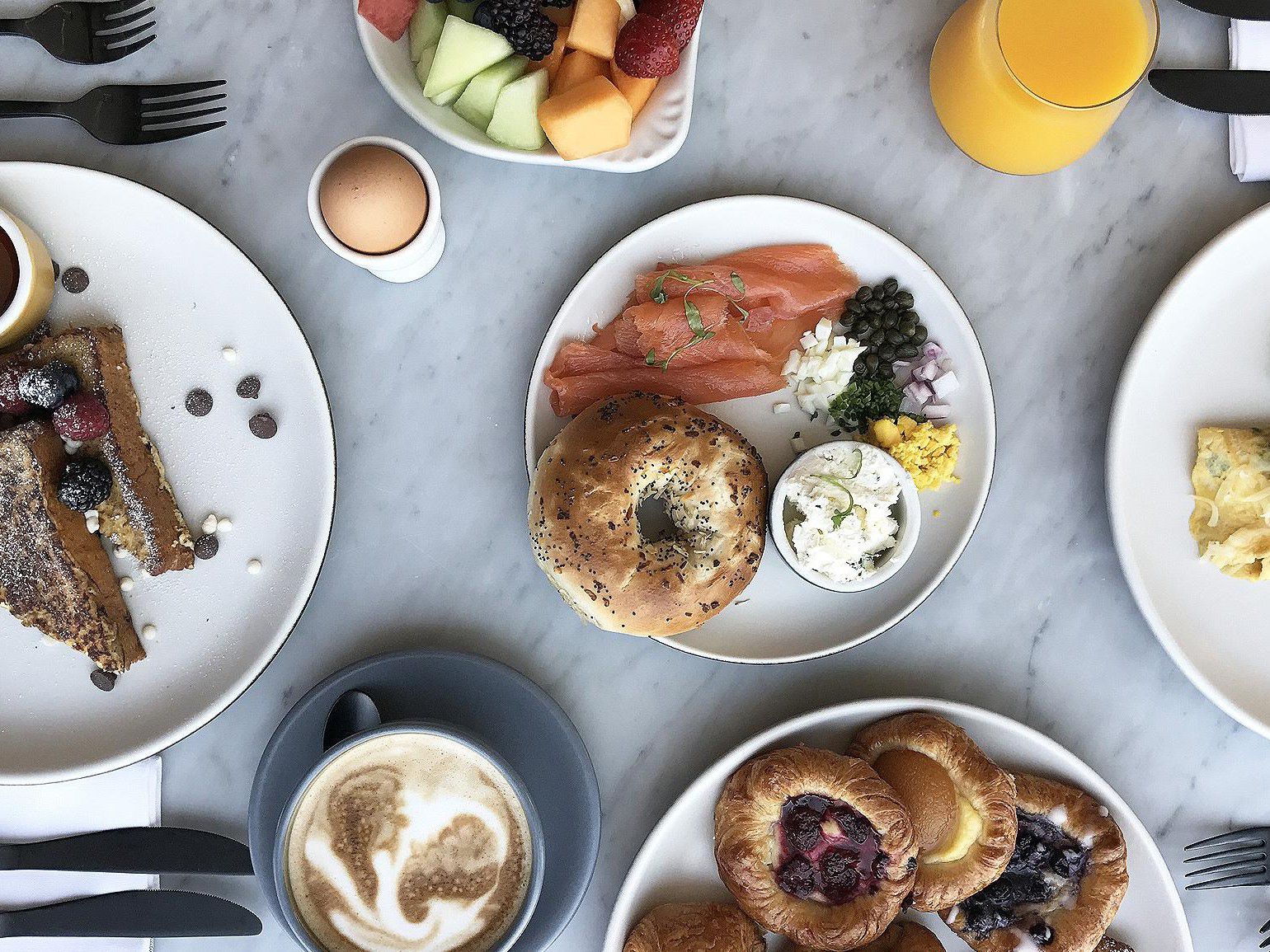 Overhead view of a breakfast spread with bagels, smoked salmon, pastries, fruit, coffee, and juice.