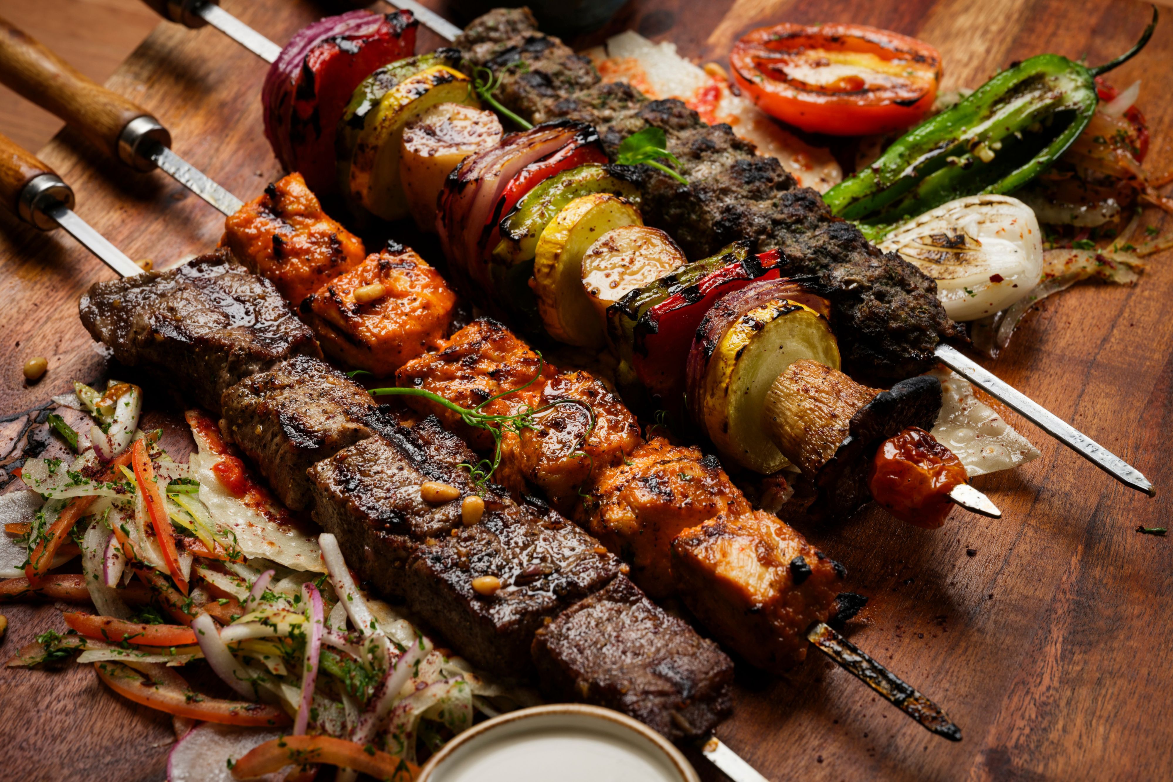 Grilled meat and vegetable kebabs on a wooden platter