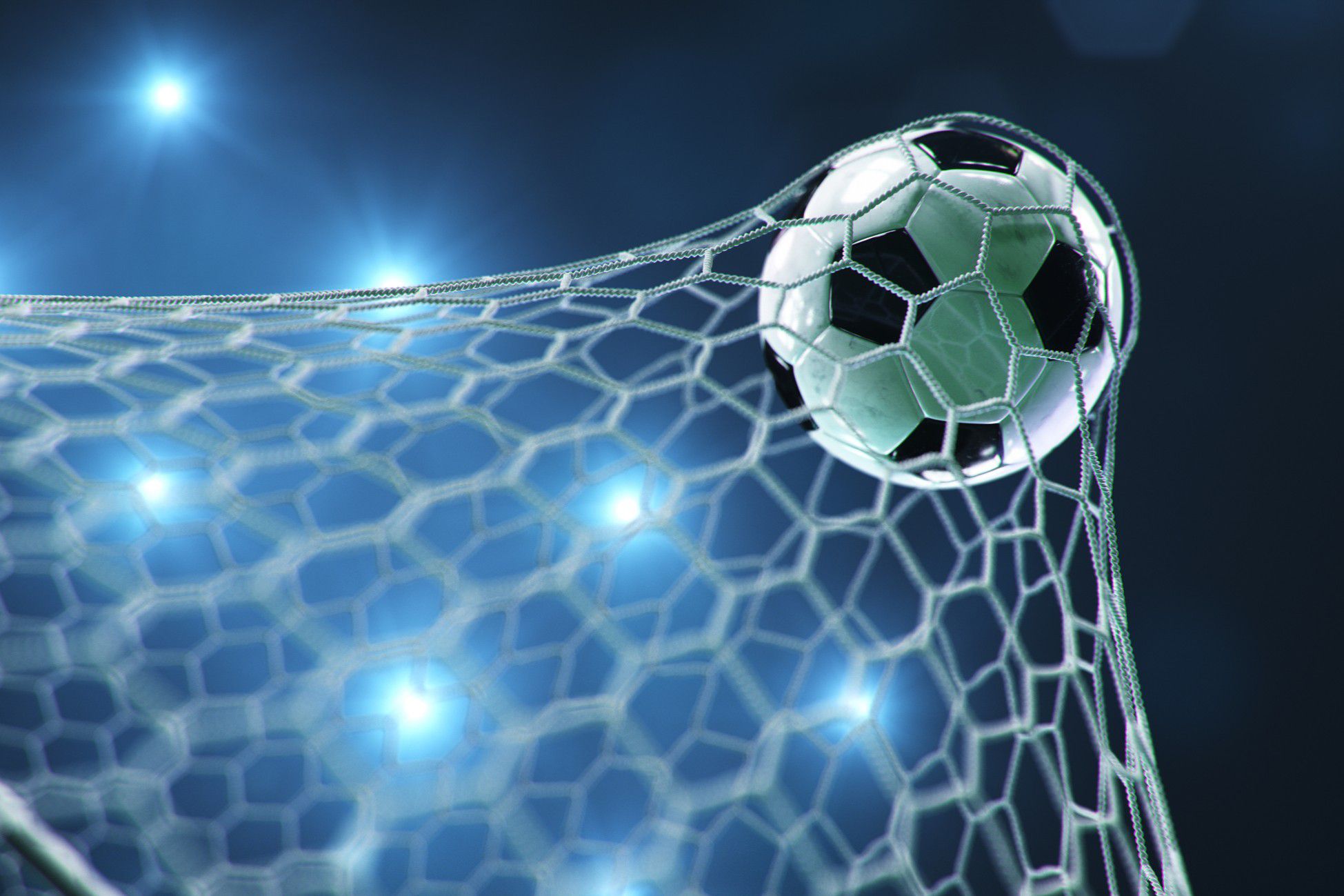 Soccer ball caught in a goal net under stadium lights