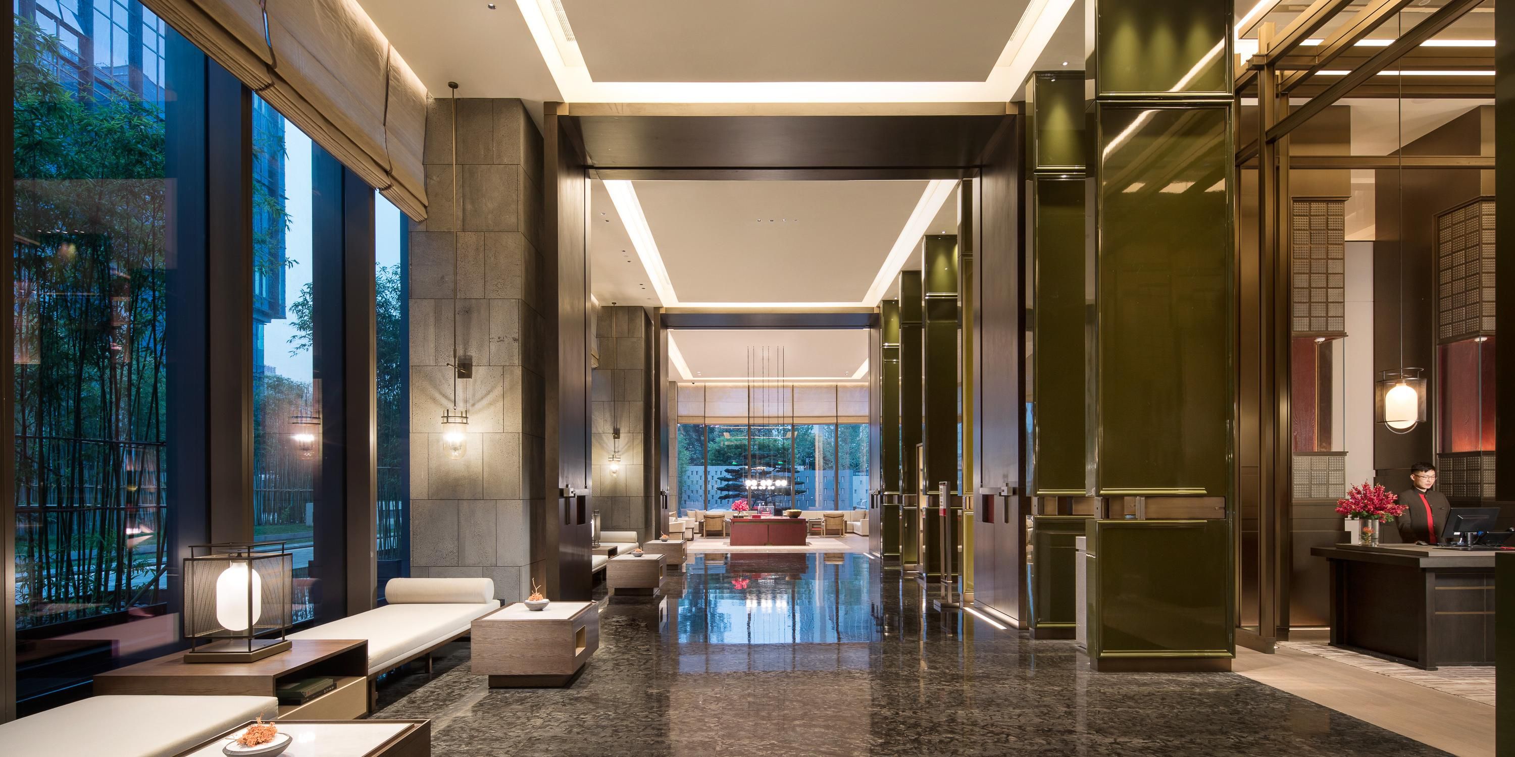 酒店建筑设计以“东方园林，唐风意蕴”为灵感，融汇中西现代美学，中式园林 “坐北朝南”和中轴对称布局，构筑出隐于闹市中的园林私邸谧境。顺沿着茂密松竹林道进入酒店，大堂天花板穿梁斗拱、柱廊和门扇再现古都大宅的气派与精美，营造出城市桃花源般的宅度假空间氛围。