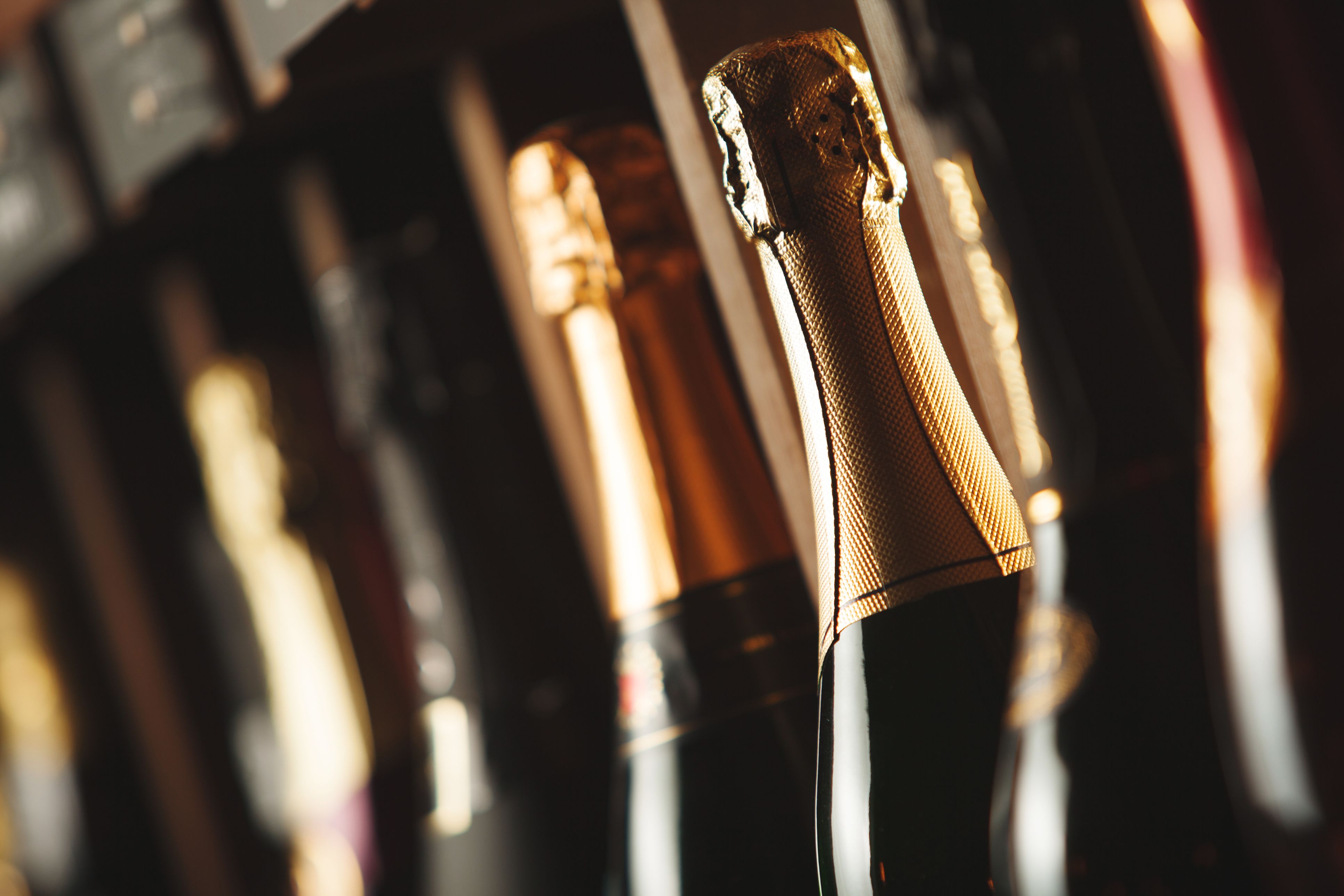 Bottles of champagne on the shelf, close-up image of alcoholic beverages in the wine cellar. Background with different expensive beverages