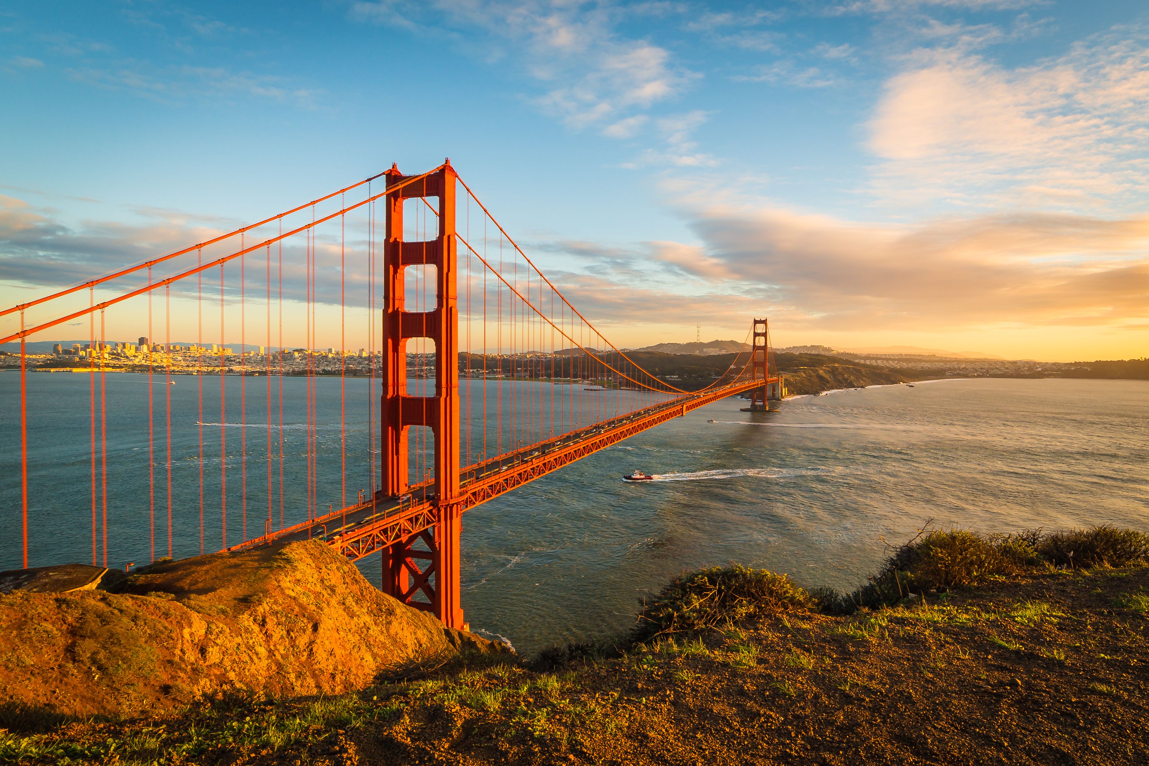 View at the Golden Gate Bridge and downtown San Francisco with clouds and with a boat under the bridge in December