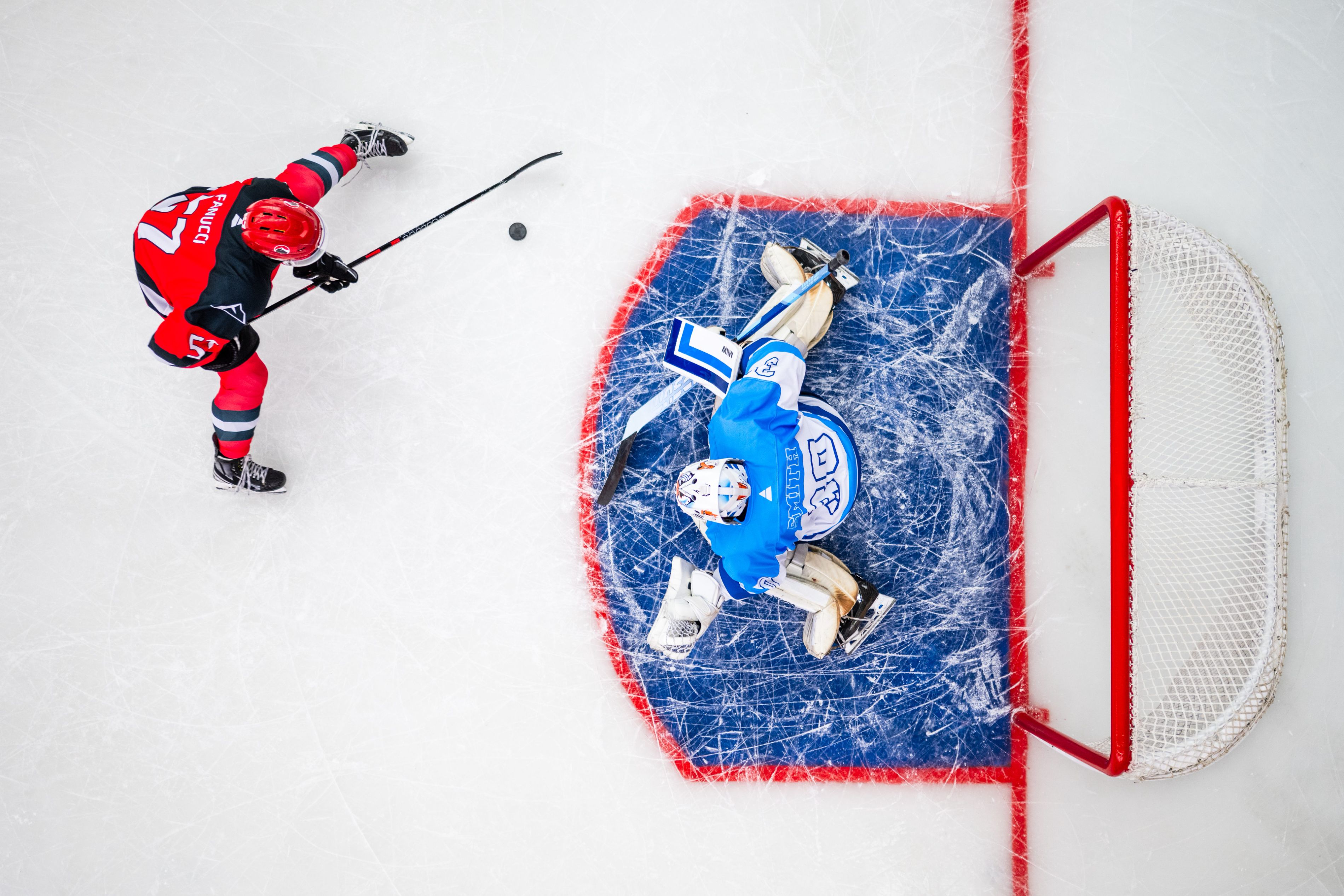 Two hockey players facing off at goal