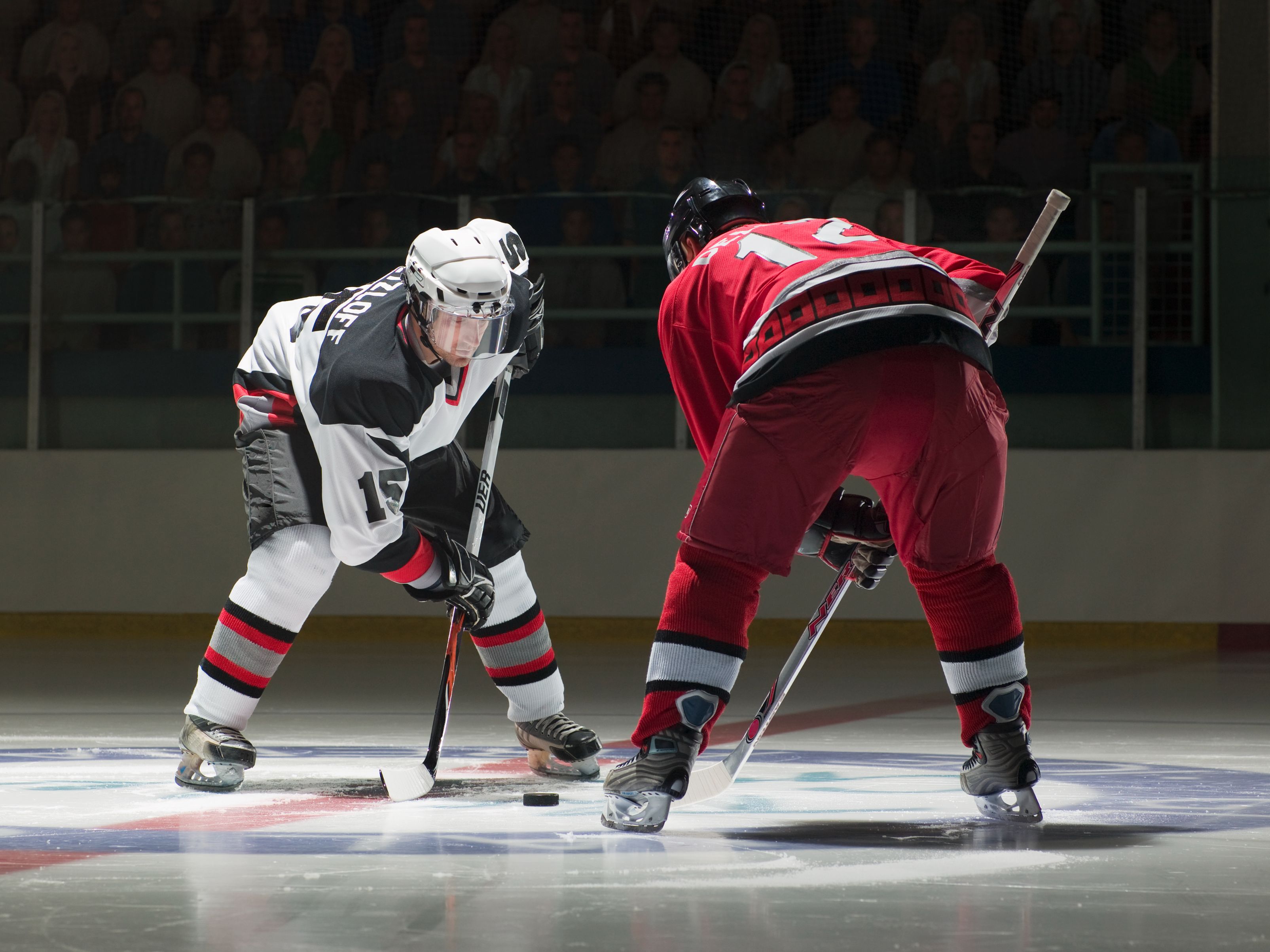 Two hockey players facing off at an ice rink